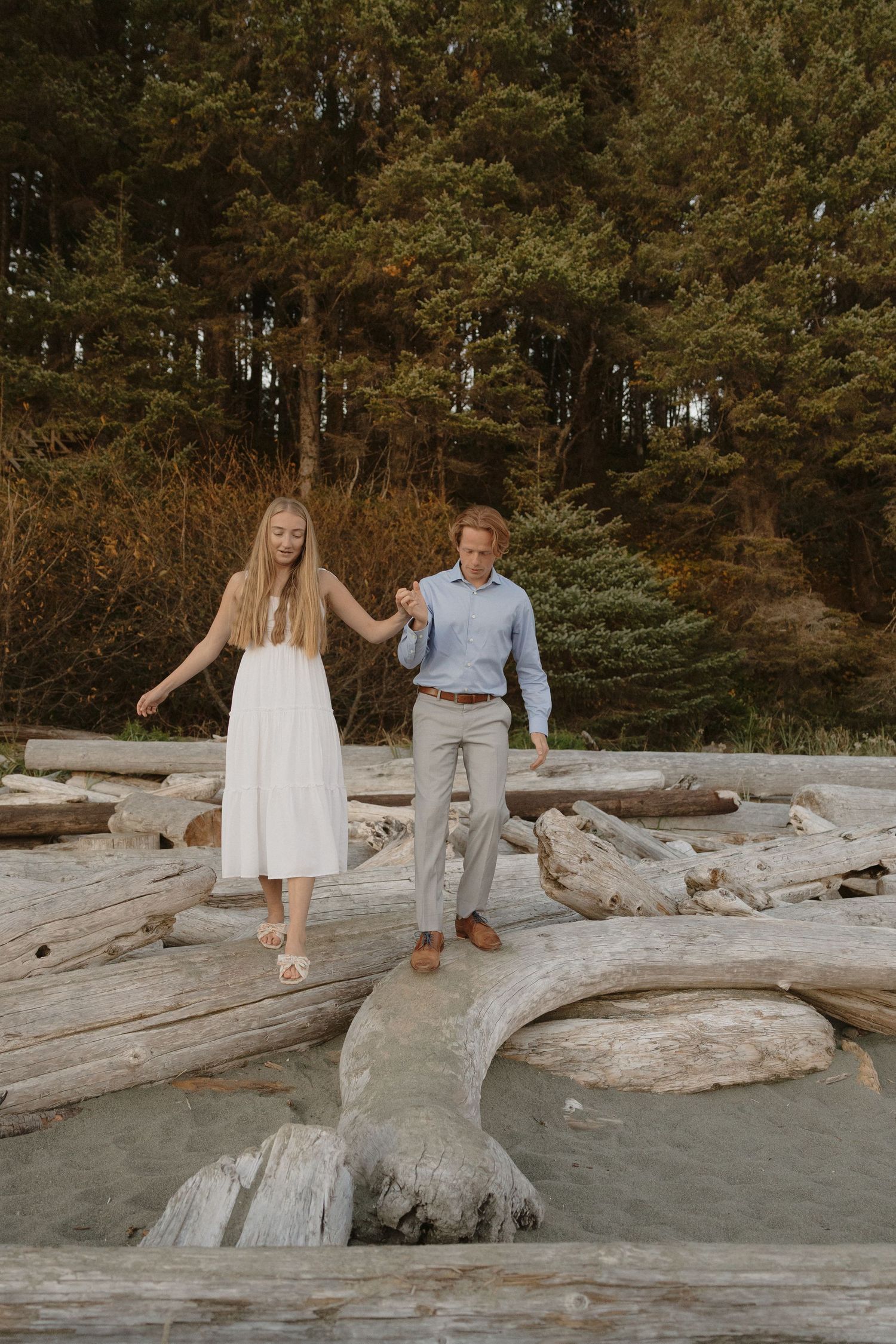 Ucluelet wedding couple playfully balancing on driftwood at sunset on the beach