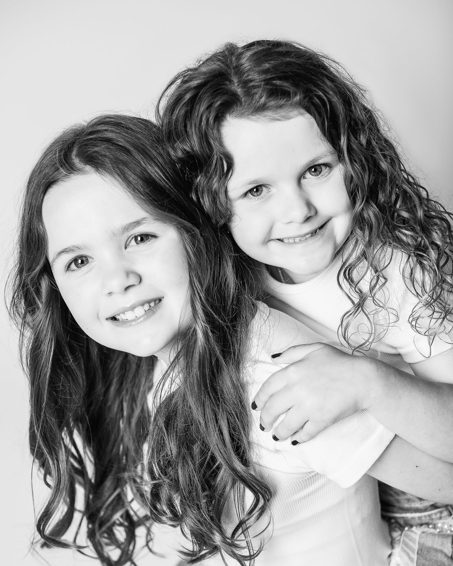 A timeless portrait of sisters embracing and laughing during a personality portrait session with Ohio photographer, FRAMED.