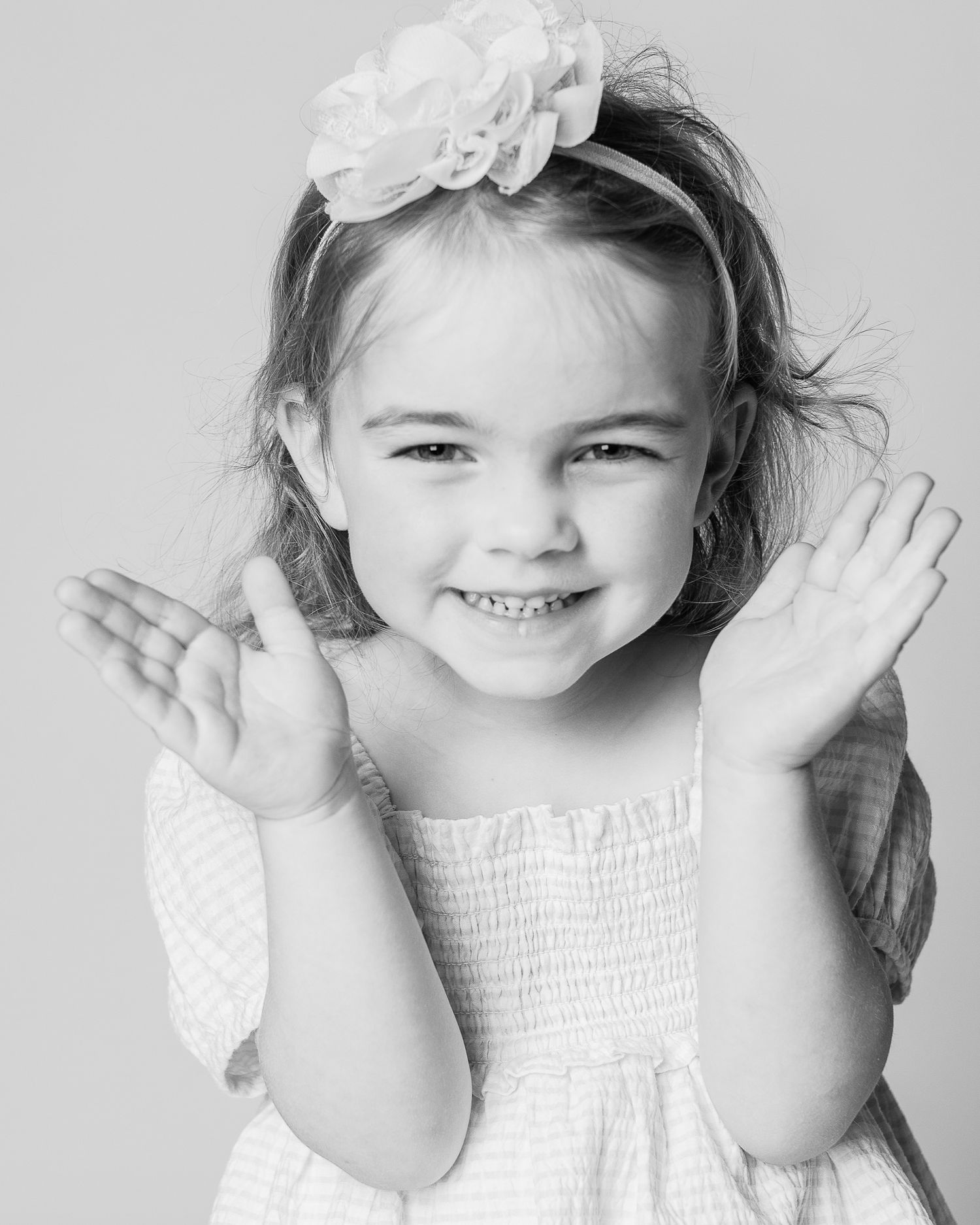 A portrait of a little girl laughing while playing peek-a-boo by Cleveland area personality portrait photographer, FRAMED.