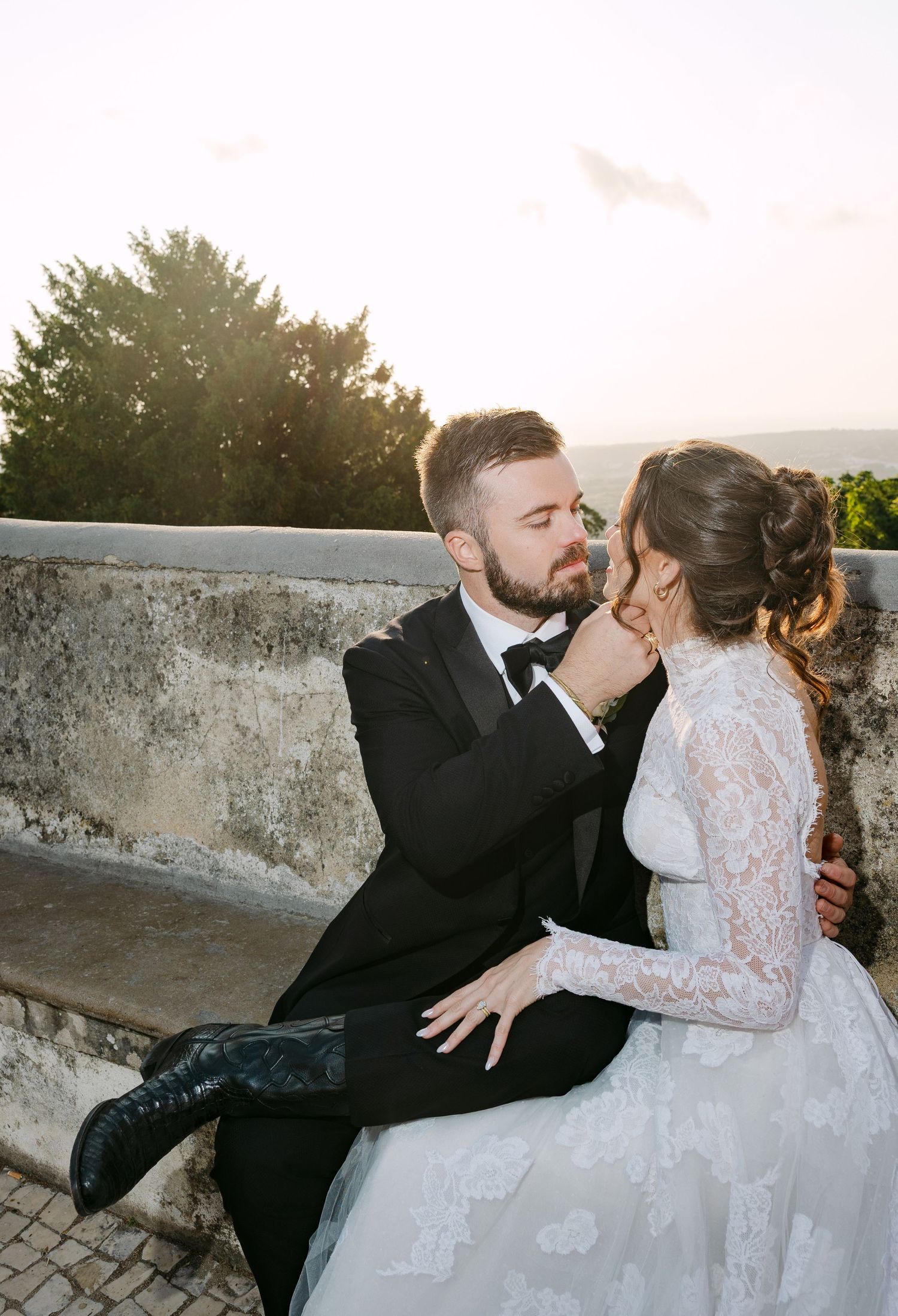 Romantic sunset moment between newlyweds sitting on stone steps.