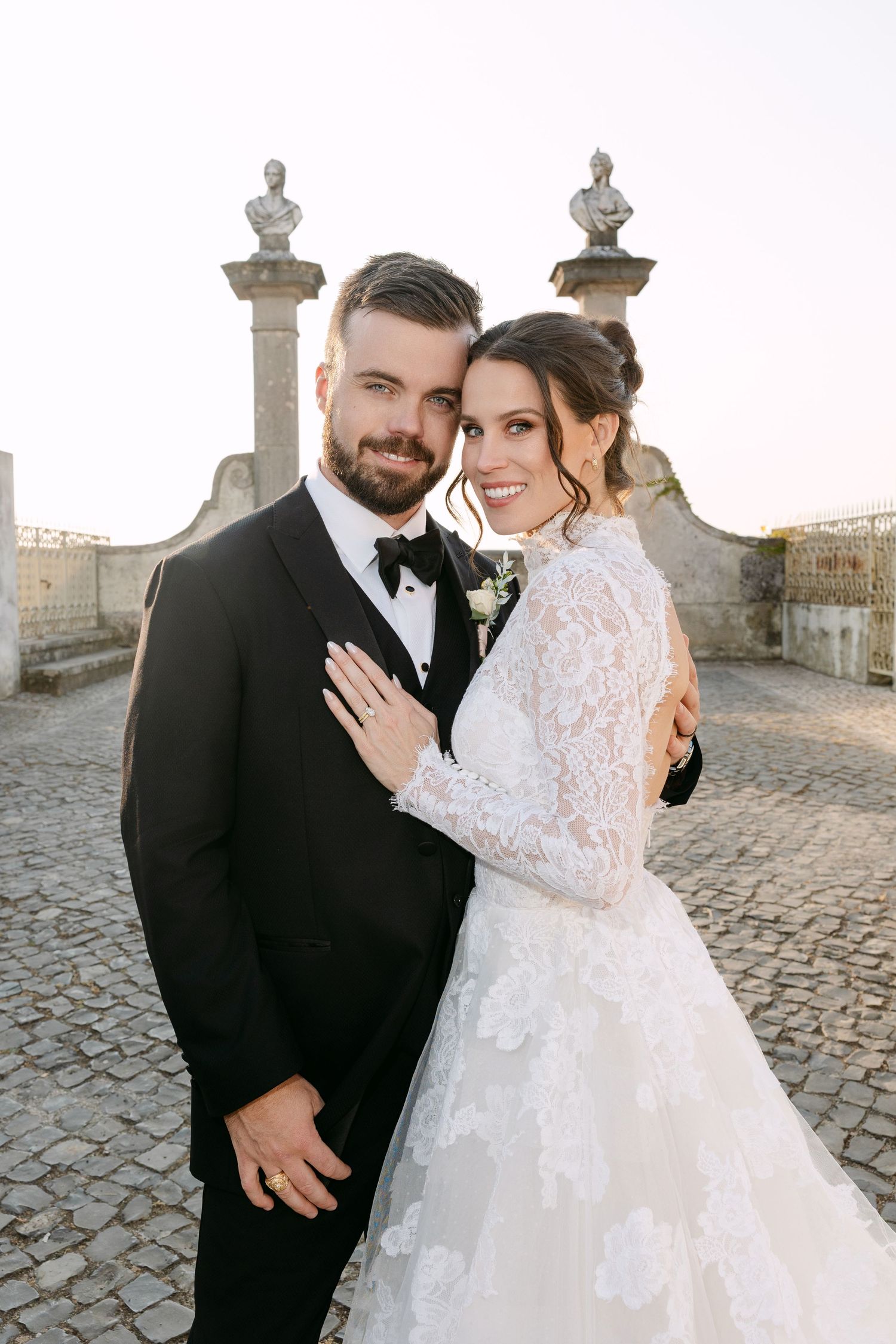 Romantic wedding portrait on cobblestone path with stone architectural details.