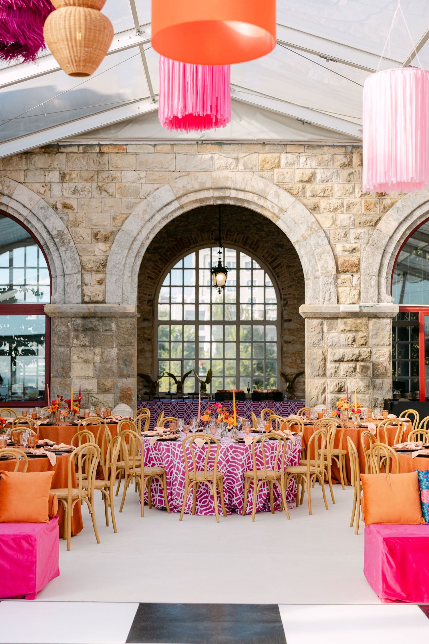 Wedding reception venue with stone arches and coral pink decor elements.