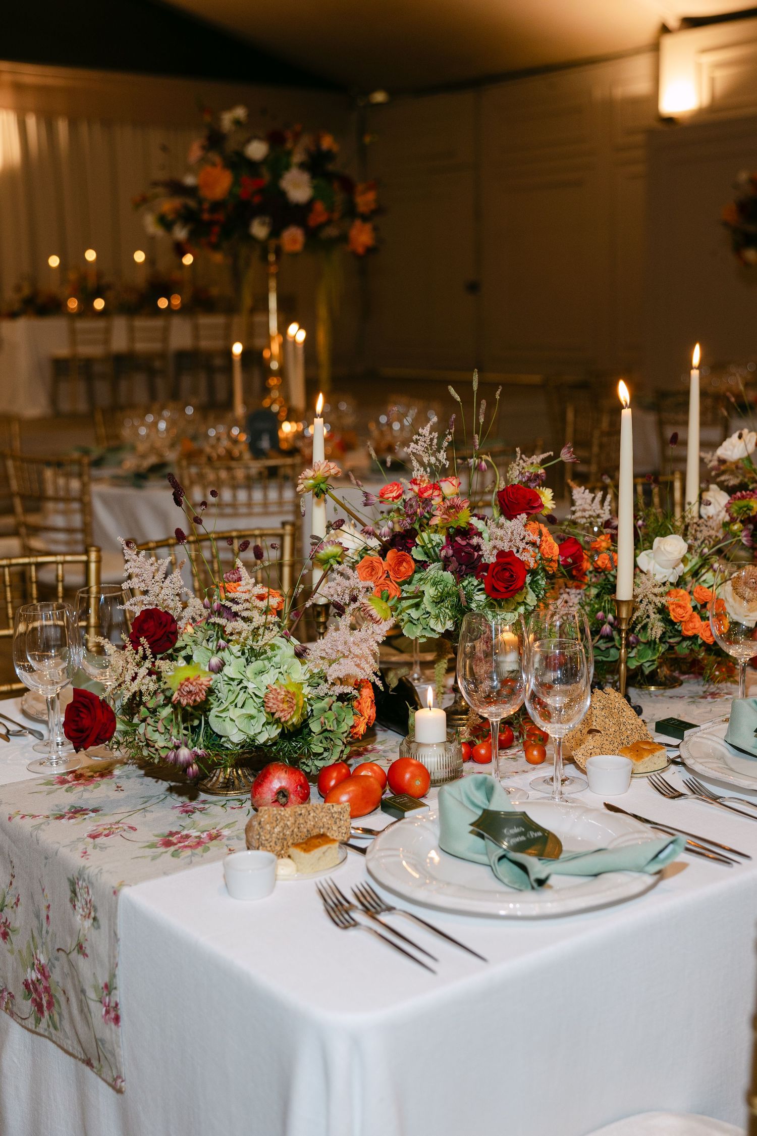 Long banquet table decorated with colorful floral arrangements and white linens.