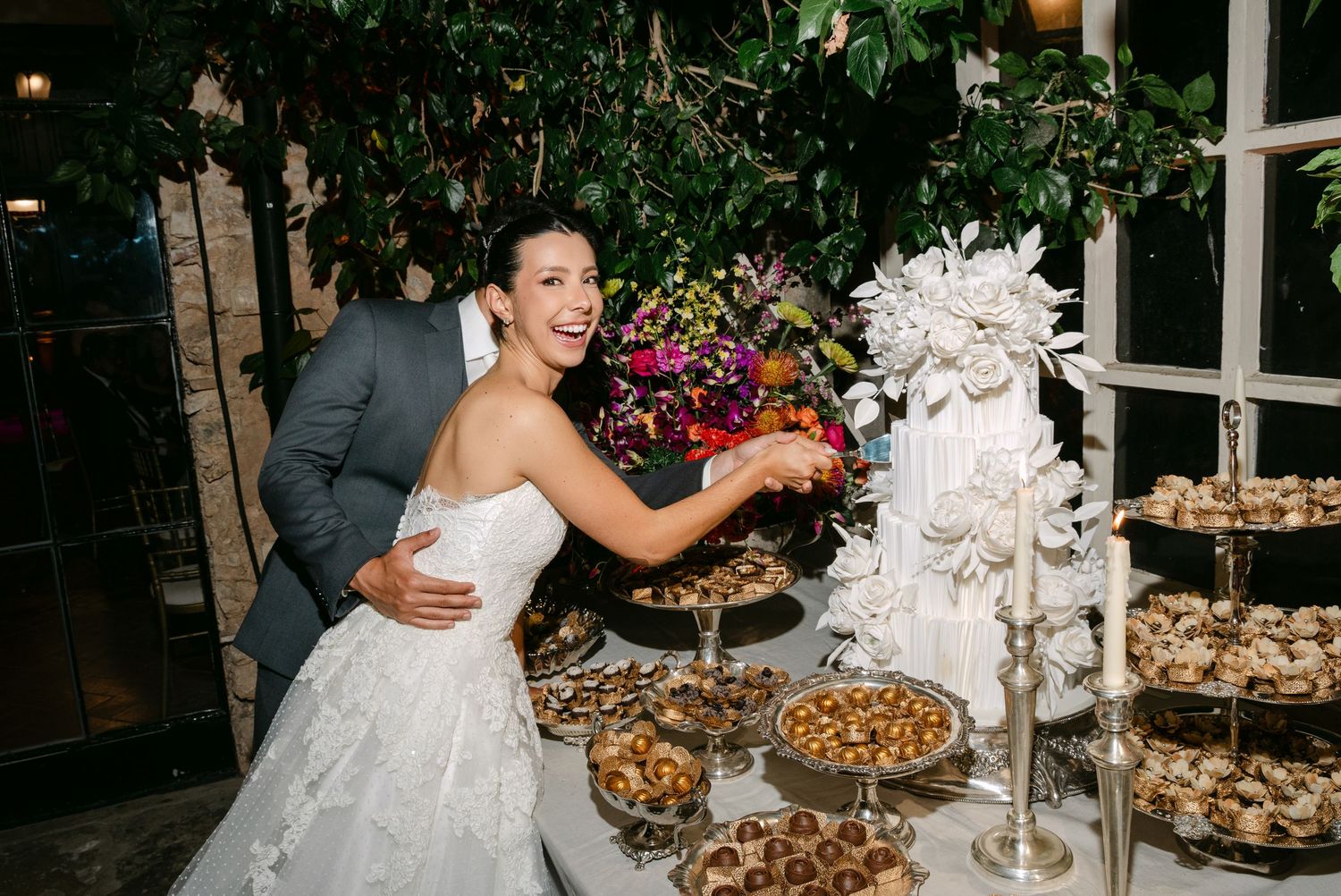 A wedding dessert table decorated with pastries and floral arrangements in an elegant setting.