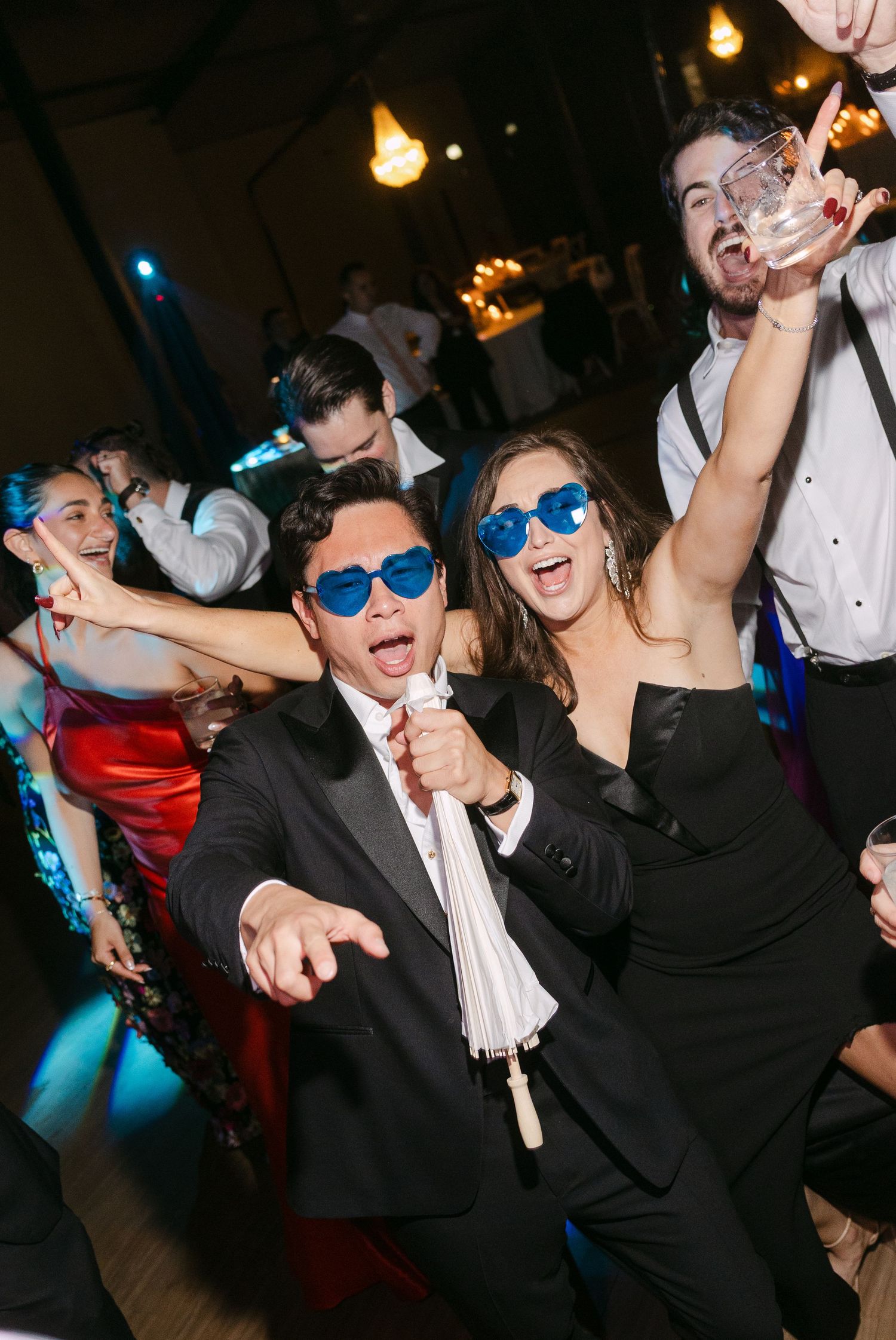 Wedding reception dance floor with guests wearing blue sunglasses and dancing.