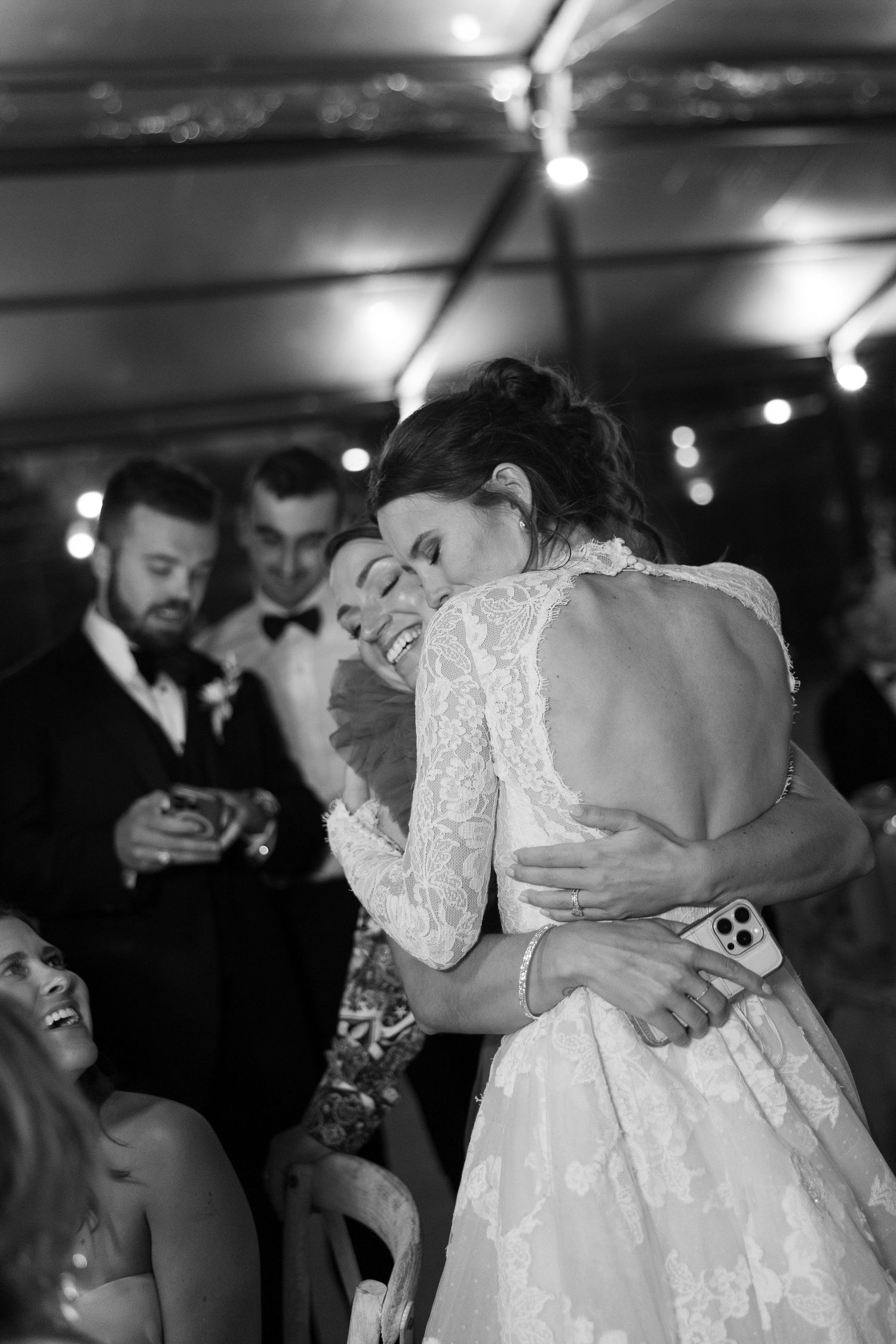 Wedding couple embracing on the dance floor surrounded by guests at their reception.
