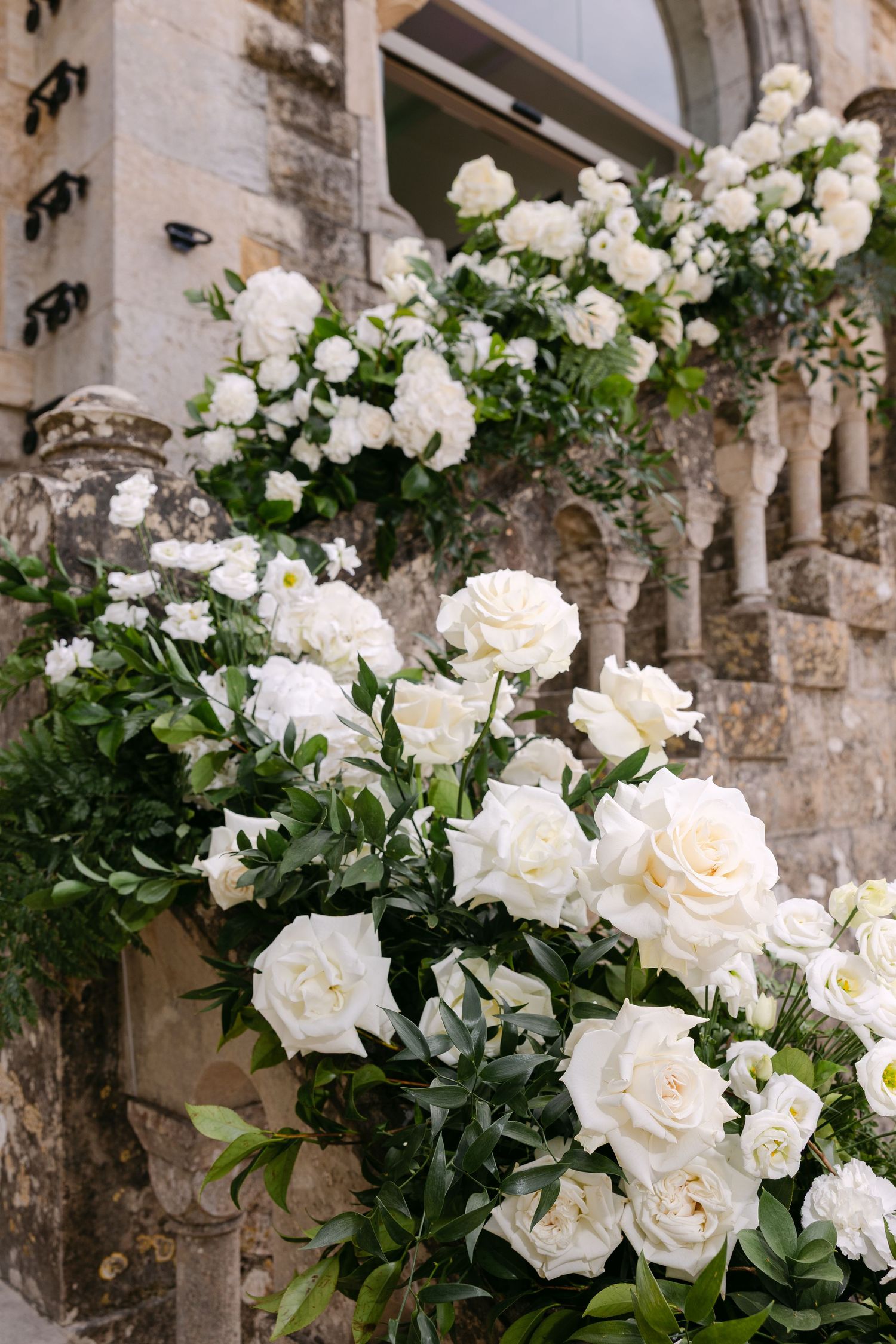 Beautiful white roses and floral arrangements adorning stone architectural details.