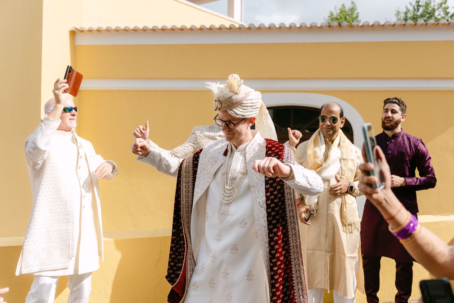 Wedding celebration with people in traditional white attire against yellow walls.