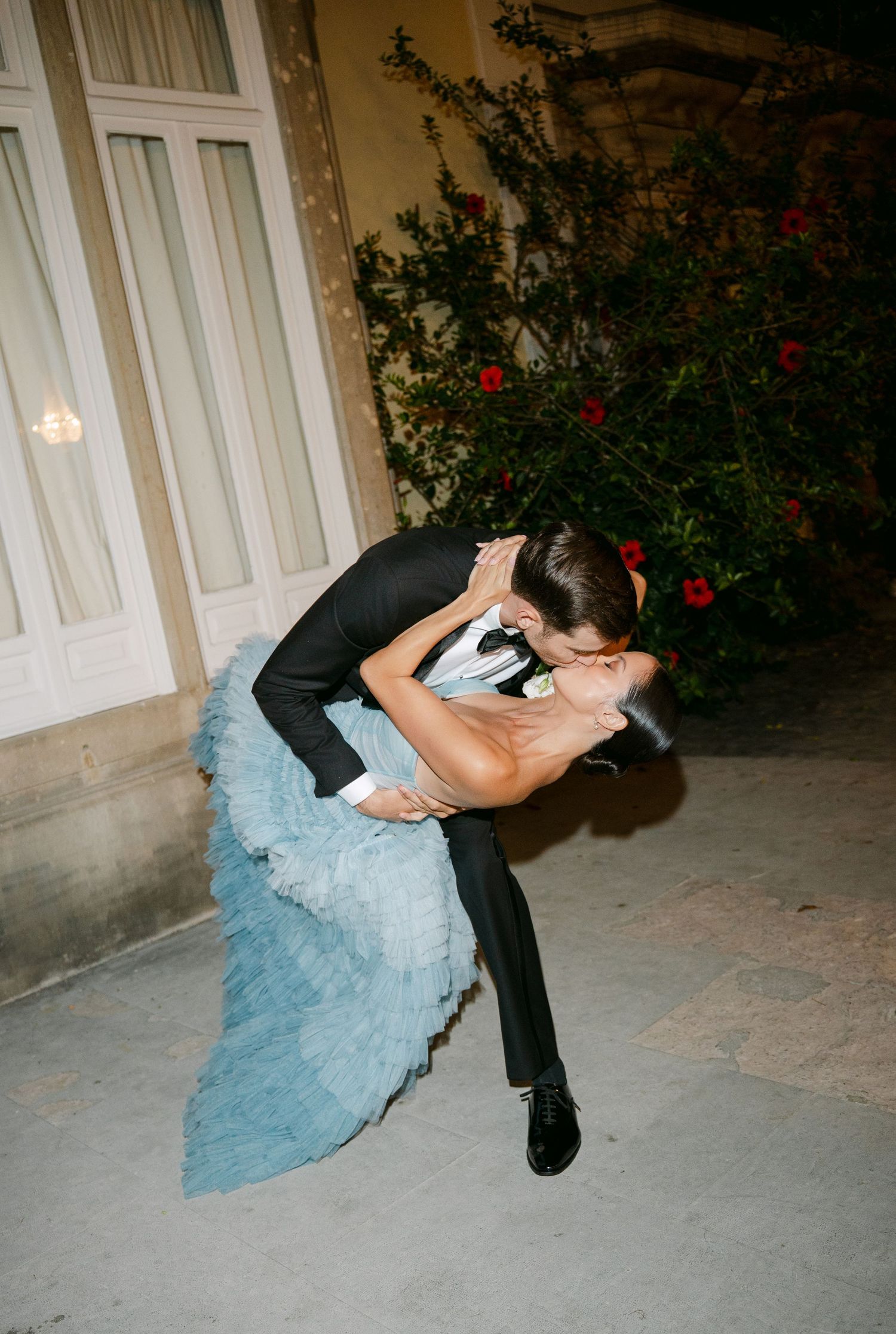 Couple performing a dramatic dip dance move in formal attire with a light blue tulle gown.