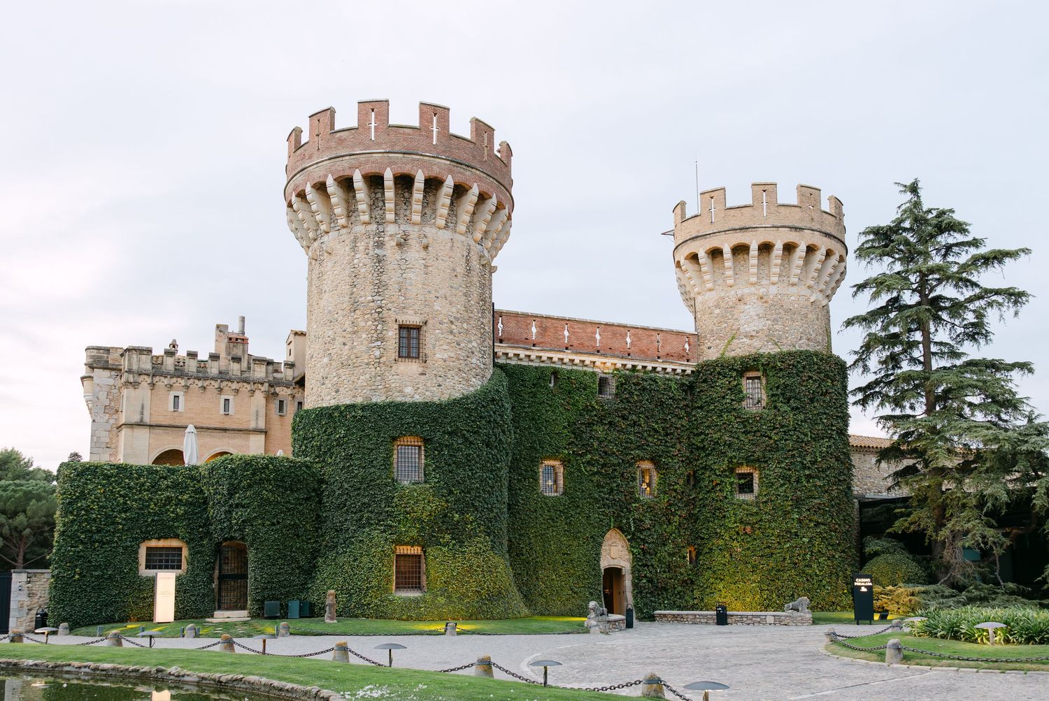 Panoramic view of a medieval castle's exterior with stone towers and ivy-covered walls.
