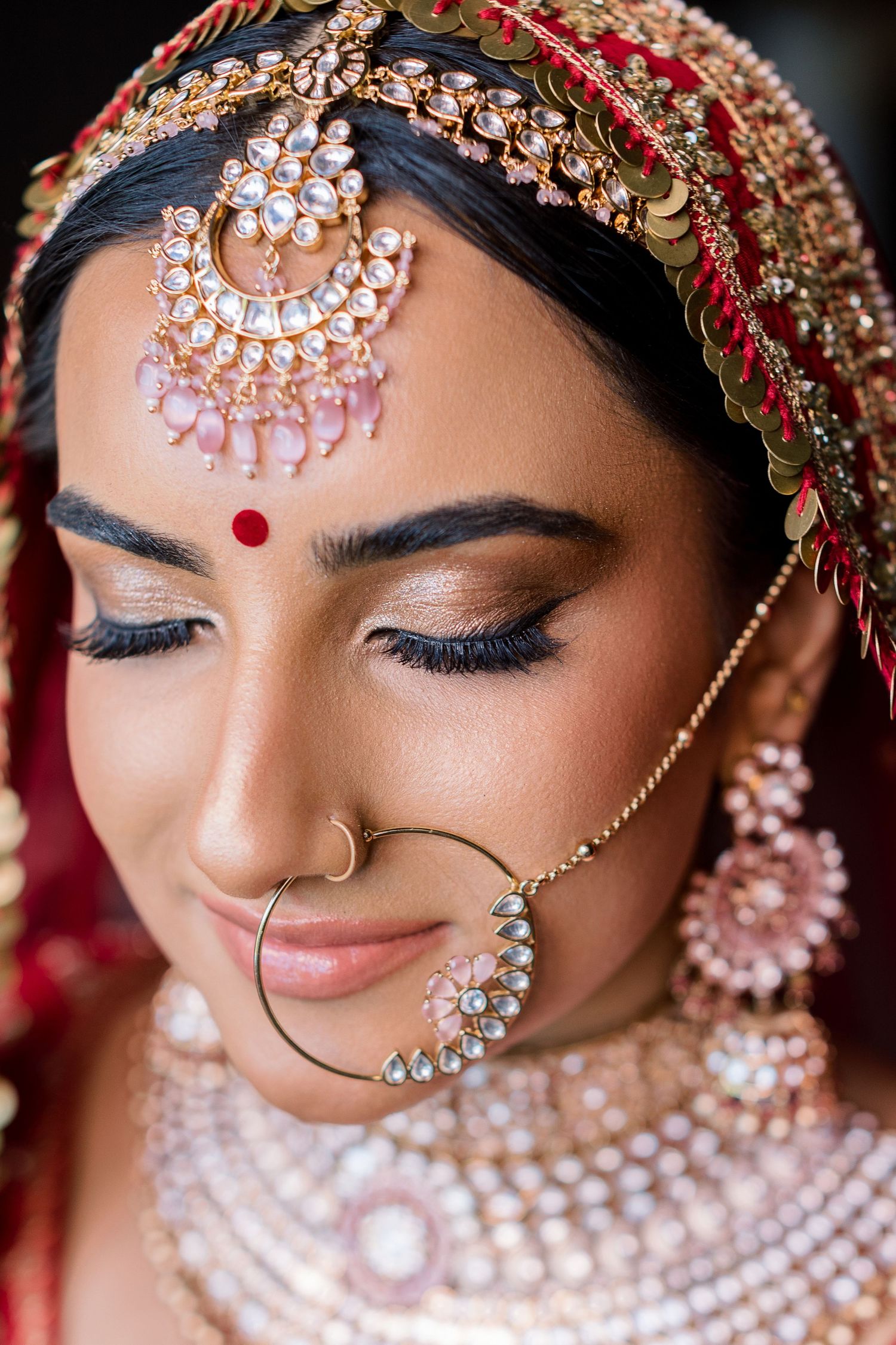 Detailed view of Indian bridal makeup and traditional jewelry with intricate design elements.