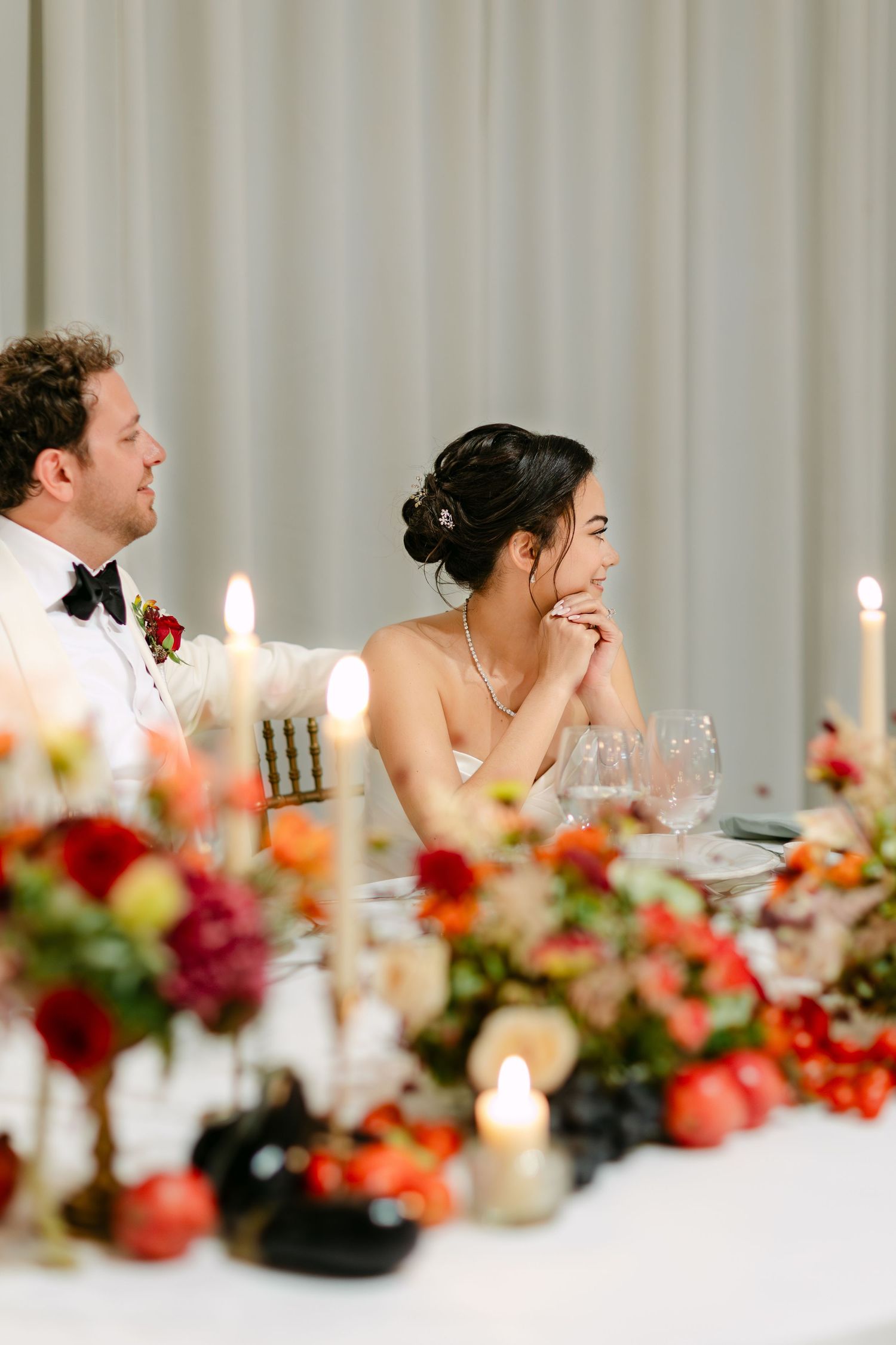 Candlelit dining table with vibrant floral arrangements and white tablecloths.