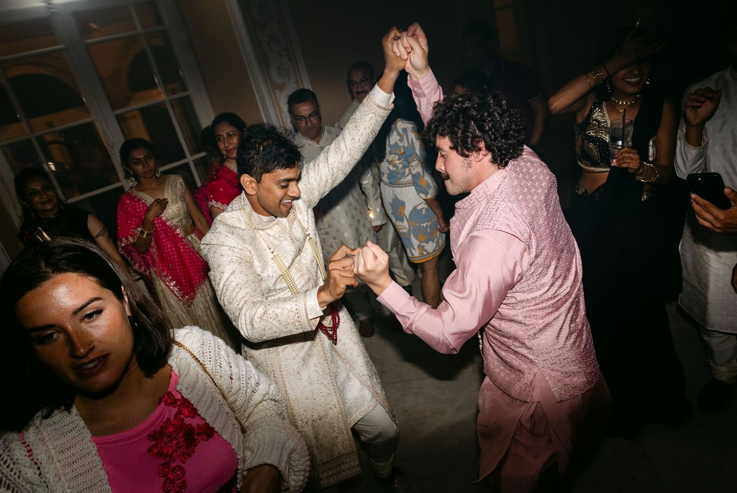 Wedding reception guests dancing and celebrating on a dark dance floor at night.