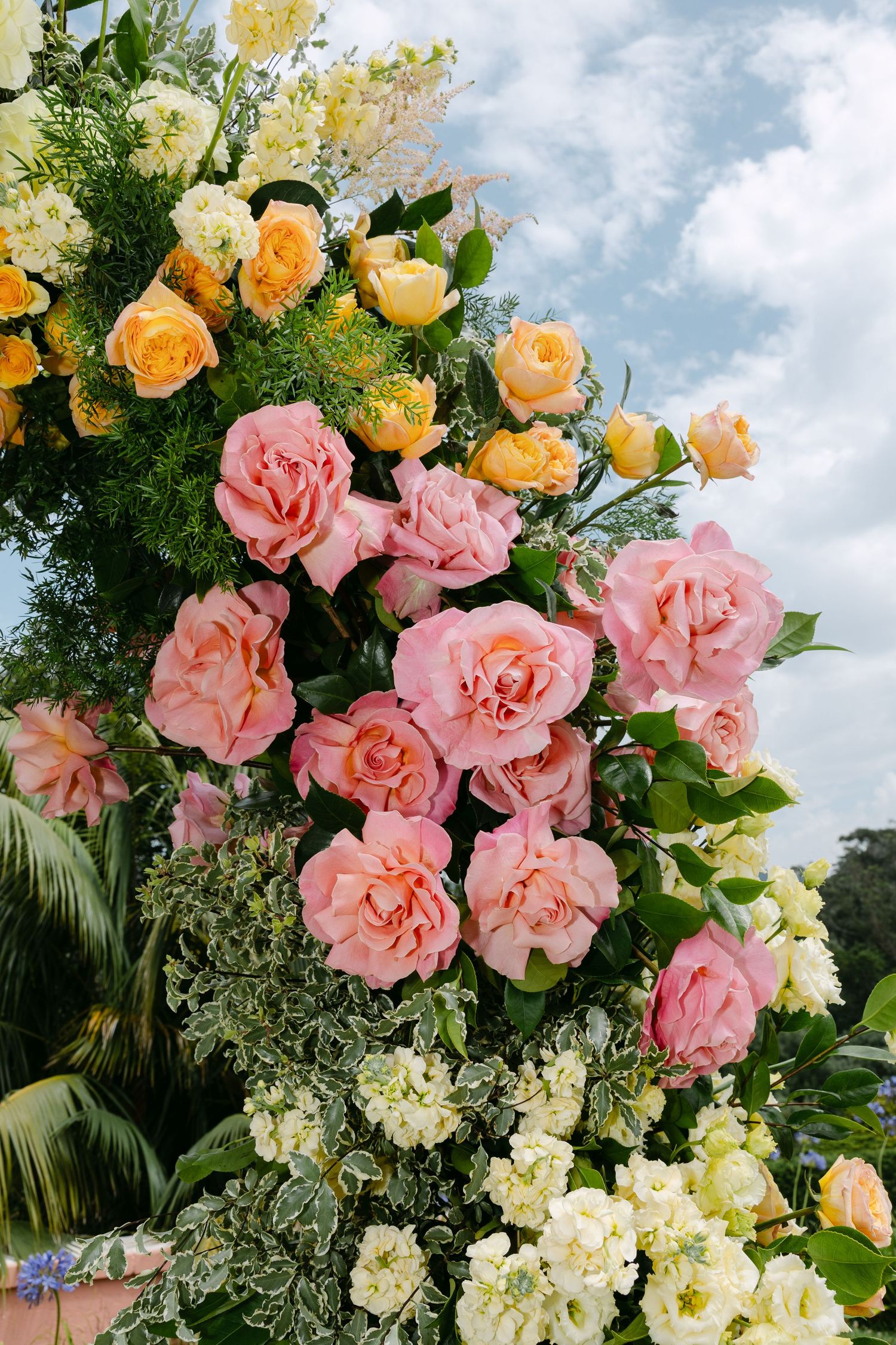 Beautiful floral arrangement featuring pink and peach roses with white hydrangeas against a blue sky.