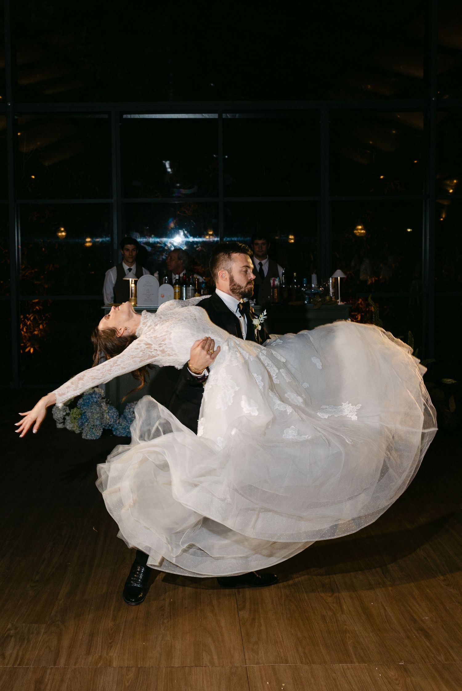 A dramatic dip during a wedding dance showcases the bride's flowing white gown.