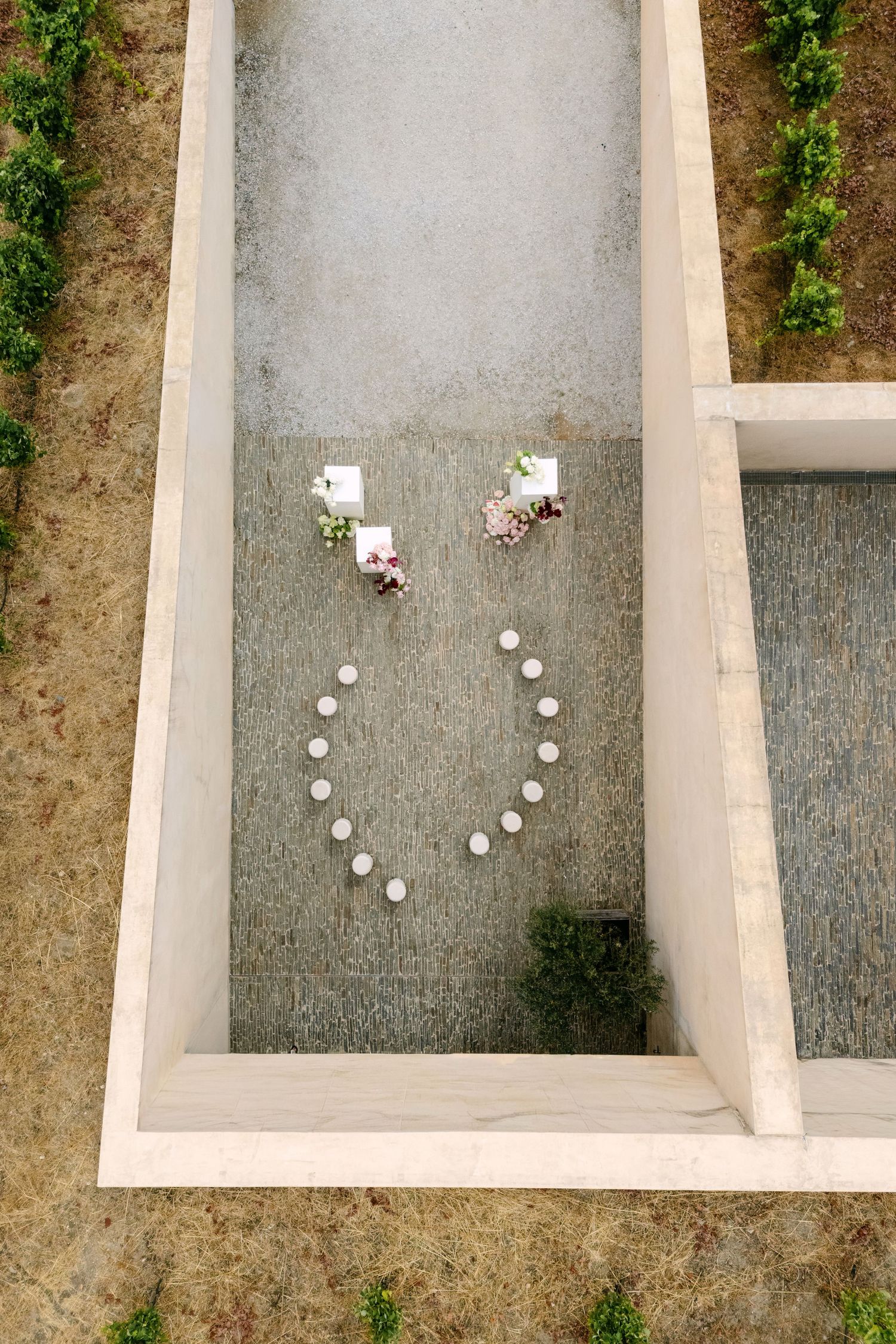 Aerial view of a courtyard wedding ceremony setup with candles arranged in a heart shape and floral arrangements.