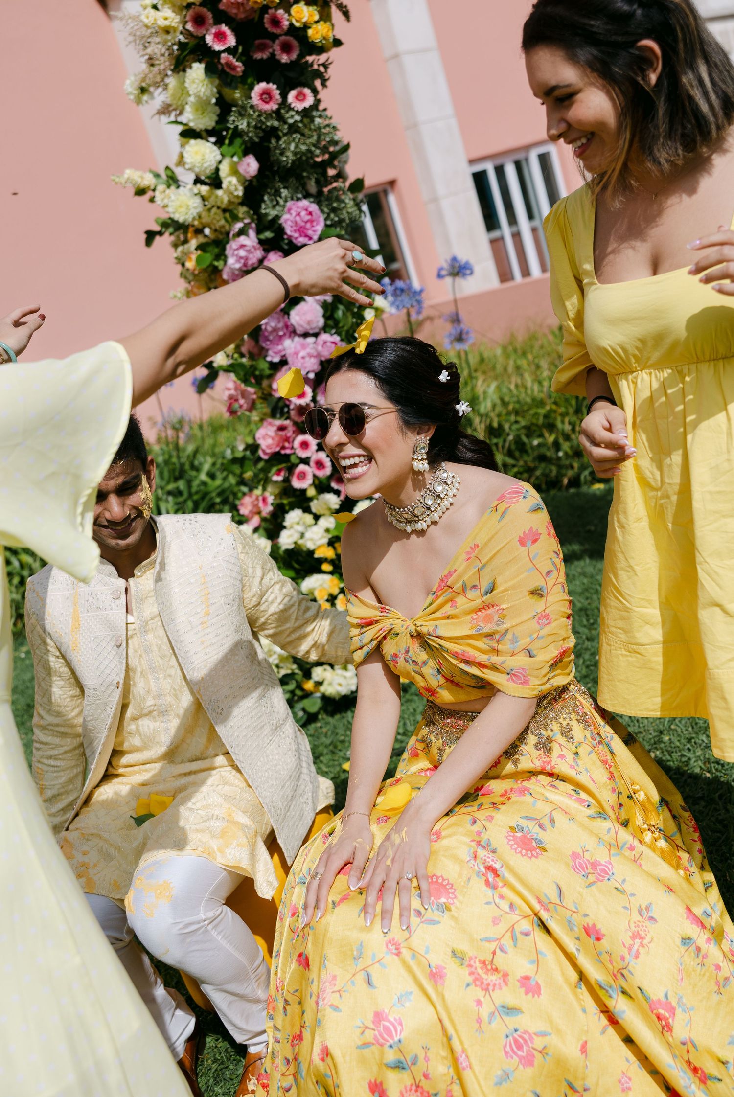 Festive outdoor celebration with people wearing yellow and white outfits in a garden setting.