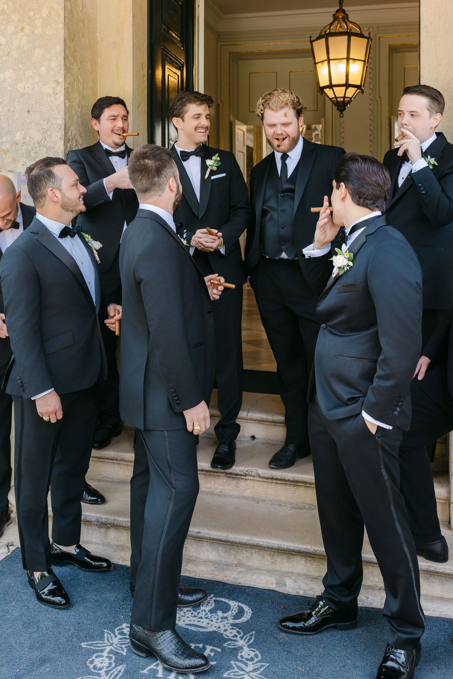 Groomsmen in black tuxedos gathered on stone steps before the ceremony.