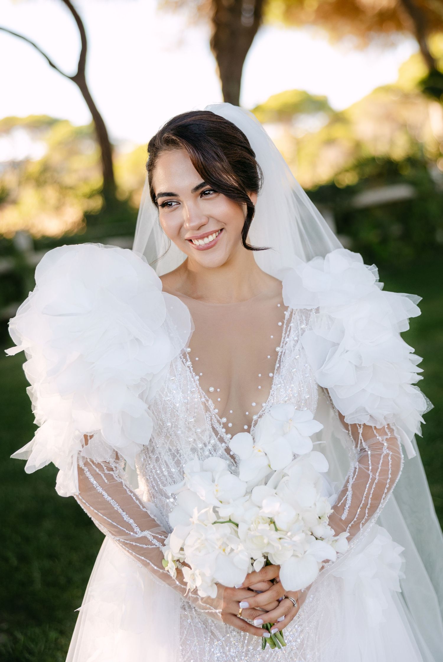 Elegant bridal portrait featuring a romantic white gown with sheer details and floral bouquet.