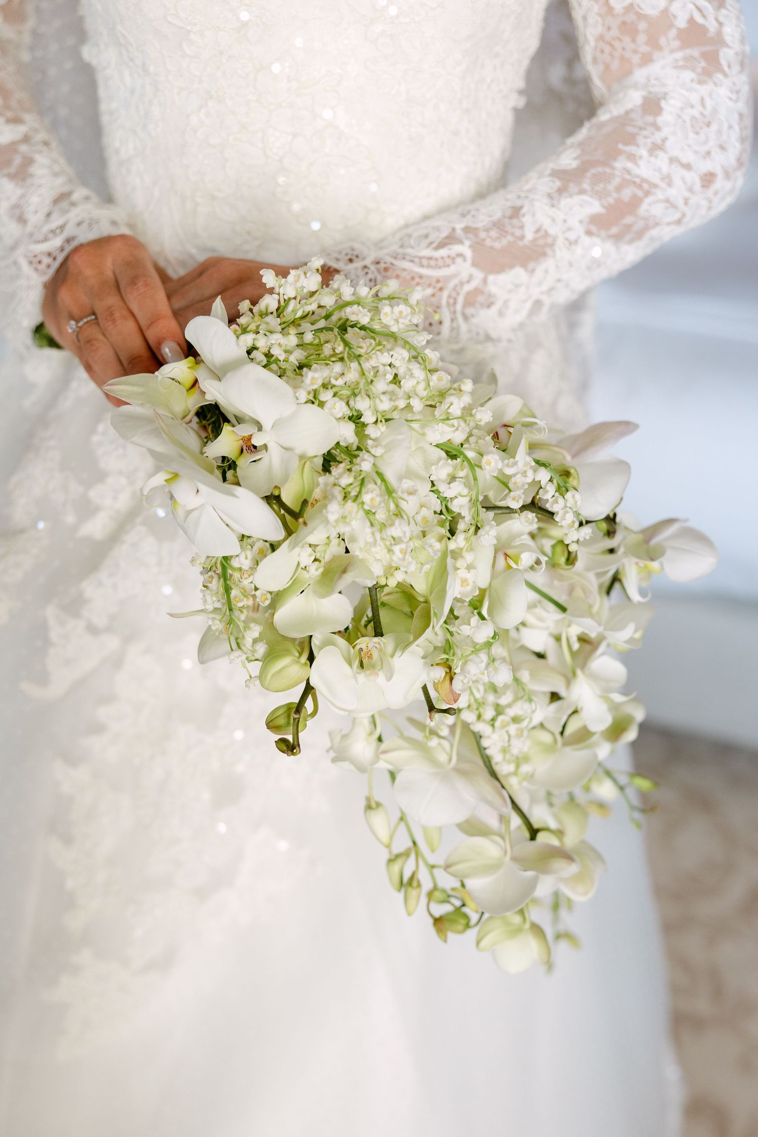 White and green cascading bridal bouquet with delicate orchids and floral details.