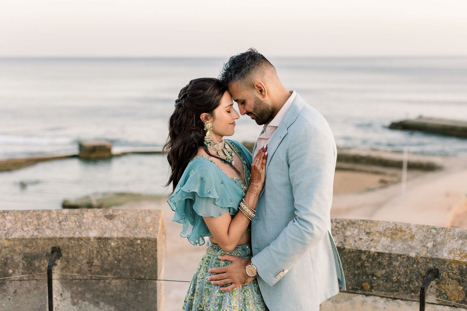 A romantic sunset portrait of a couple embracing by the ocean.