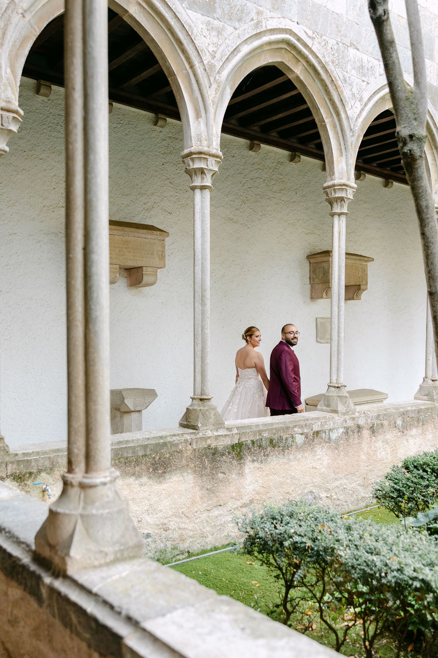 Wedding photography in a beautiful cloister with Gothic arches and garden views.
