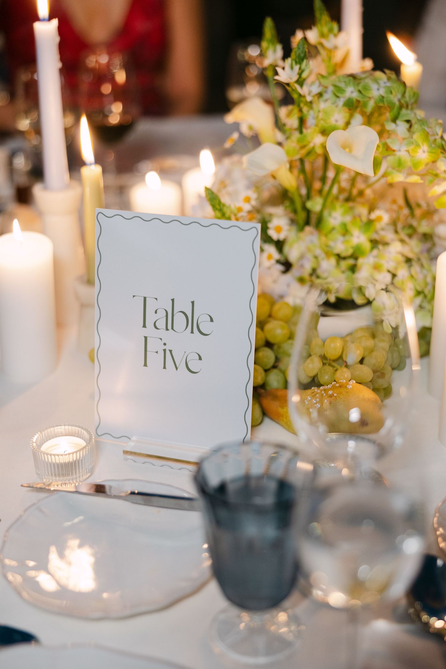 Elegant wedding reception table settings with candles and floral centerpieces.