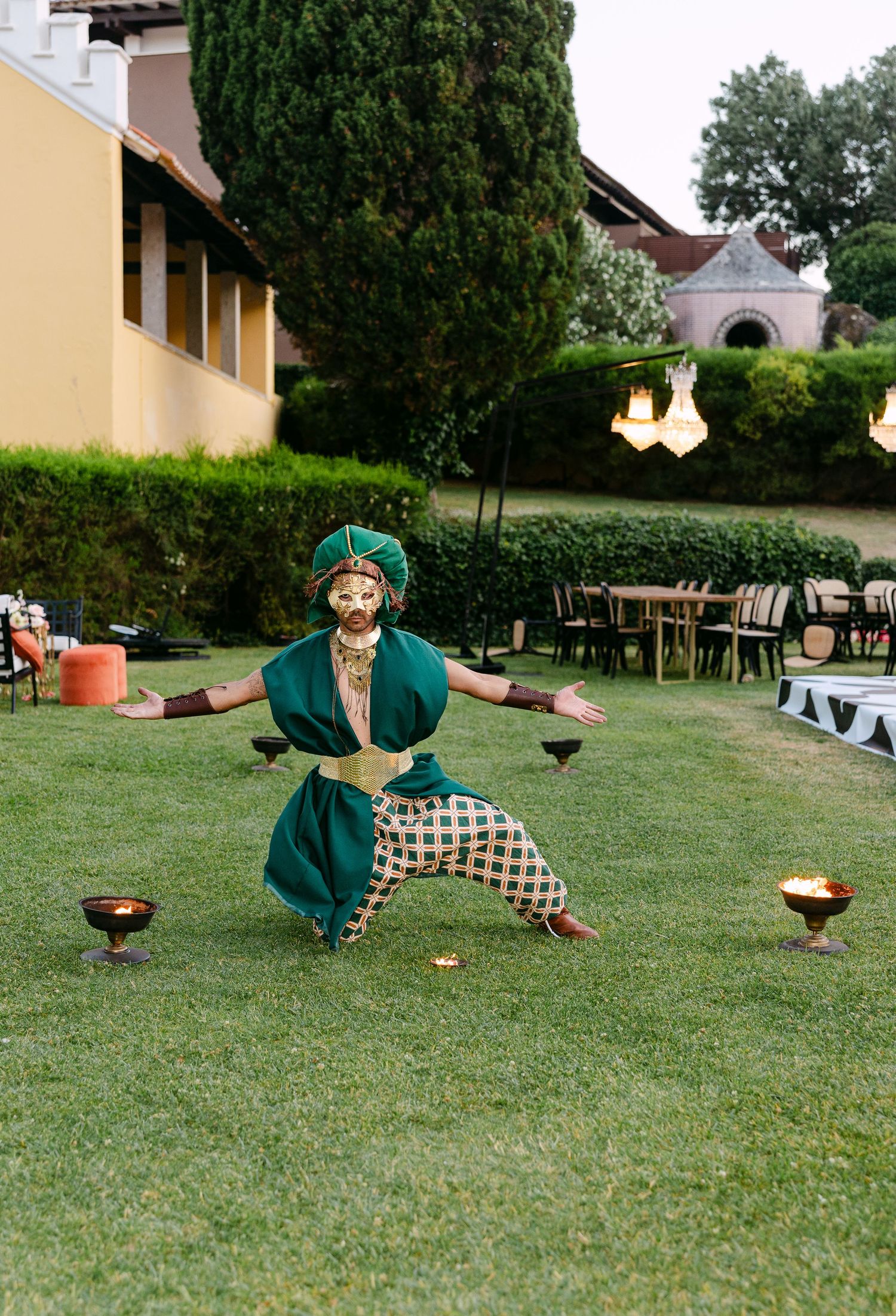 Person in emerald green outfit performs playful poses on grass lawn.