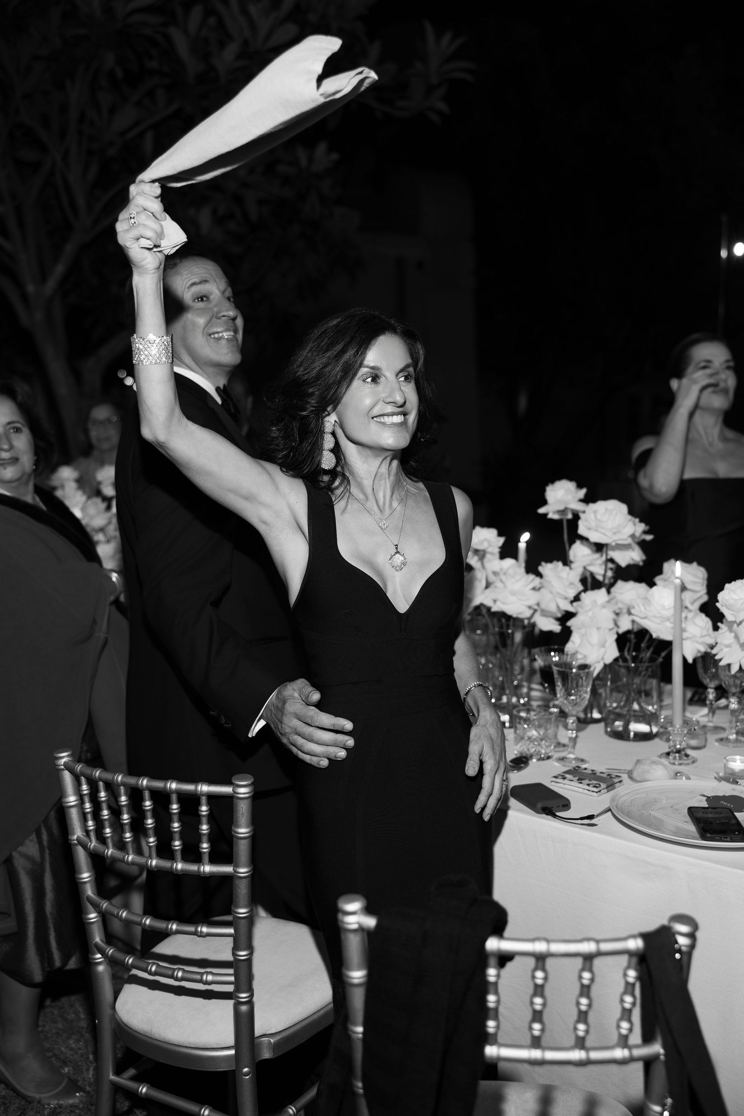 Wedding reception guests dancing and celebrating at tables decorated with white floral centerpieces.