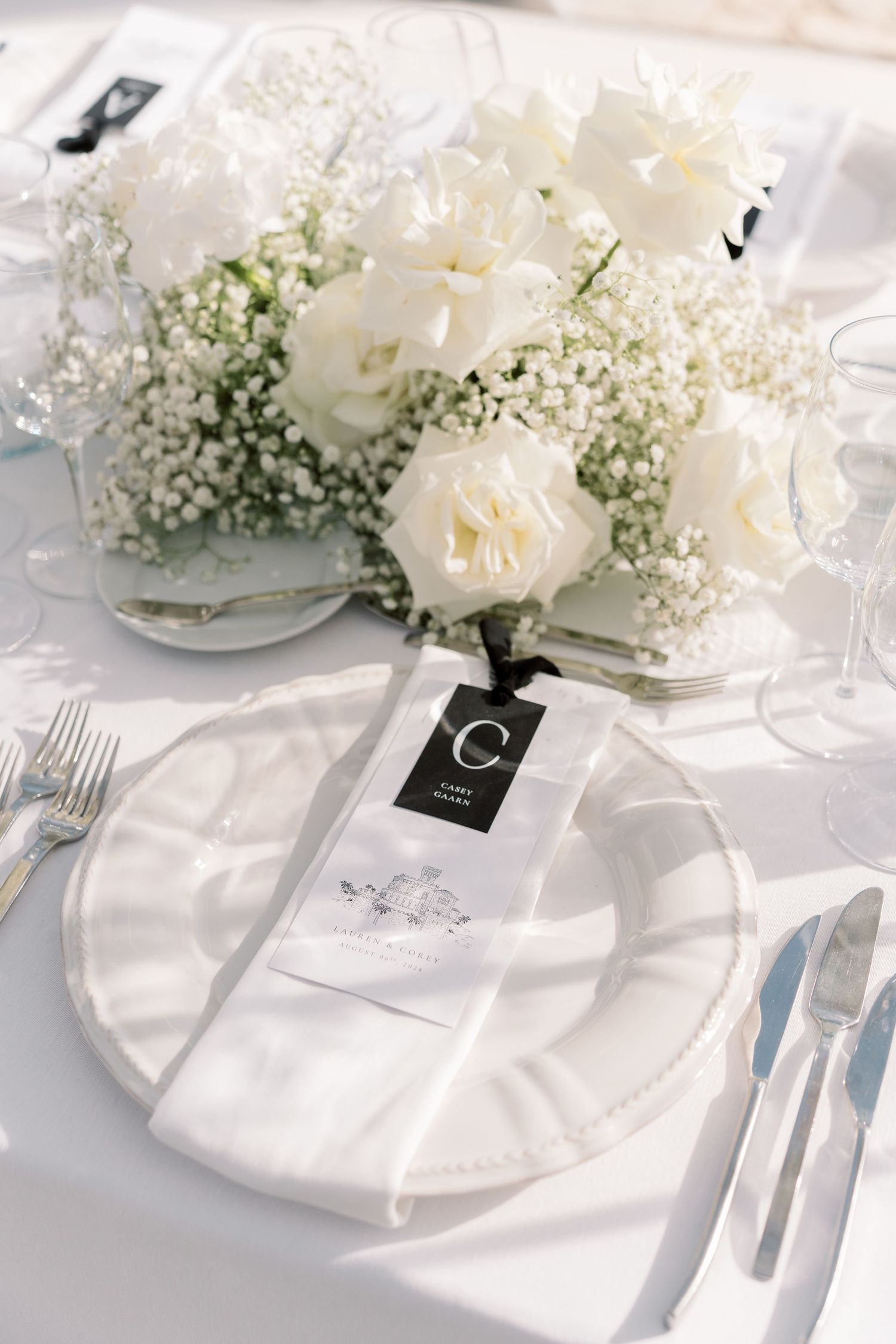 Elegant white table setting with baby's breath and rose floral centerpieces.