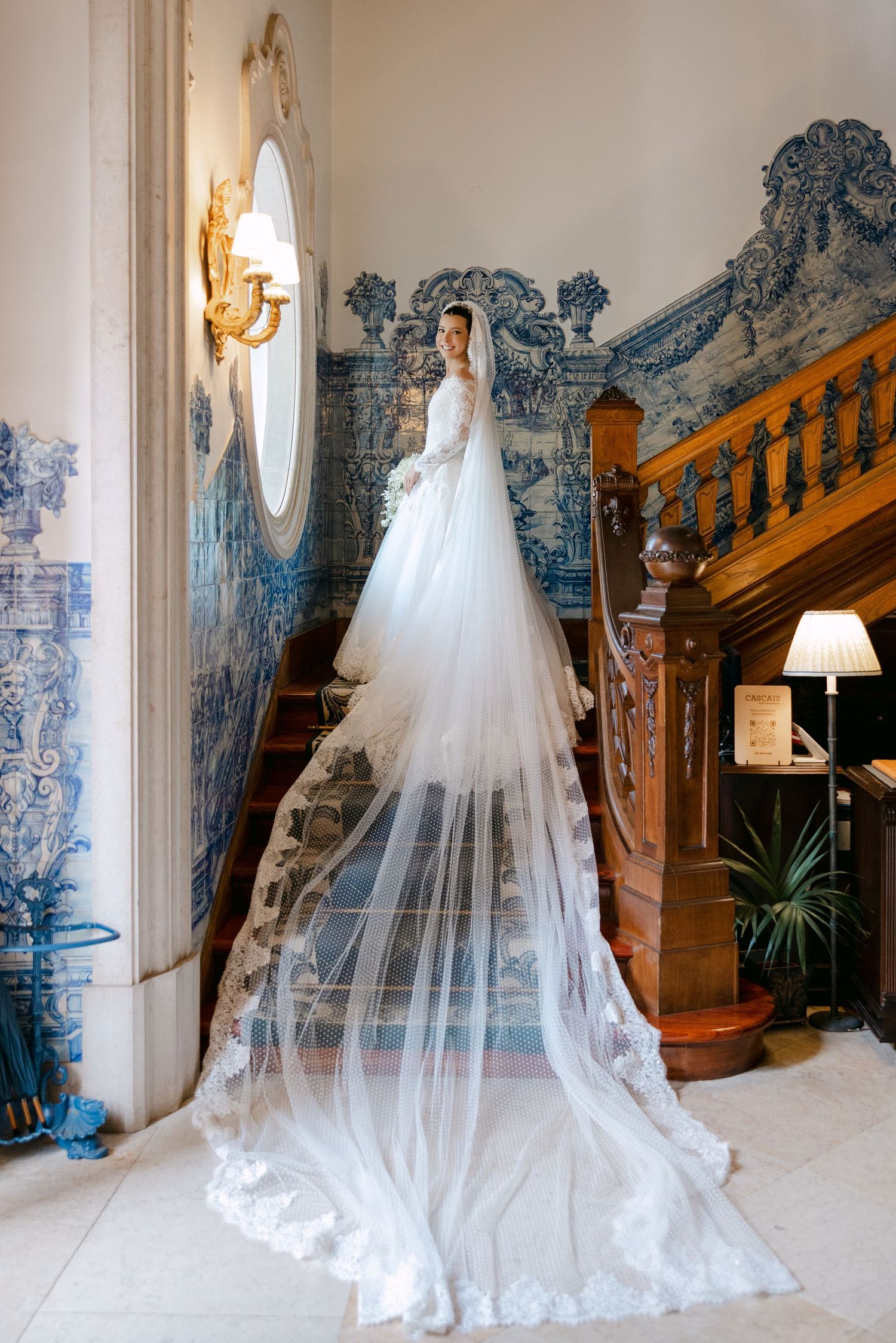 A stunning bridal portrait showcasing a flowing white wedding gown and veil against blue and white tiled walls.