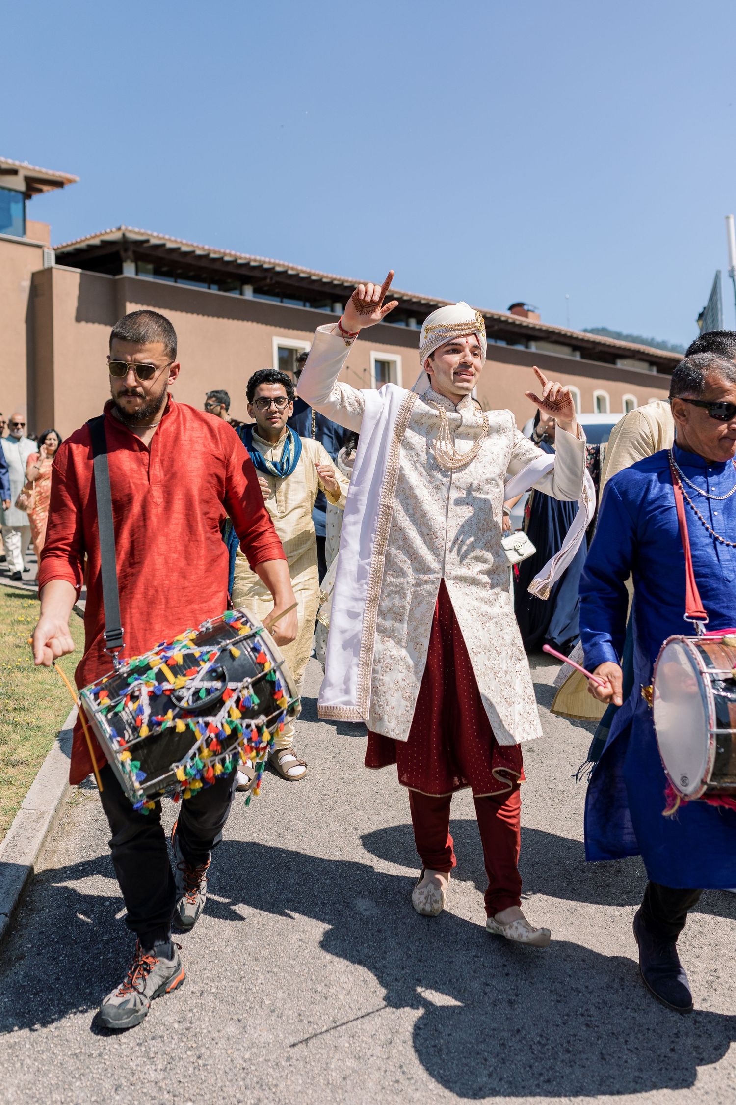 Festive procession of people in colorful traditional outfits walking outdoors.