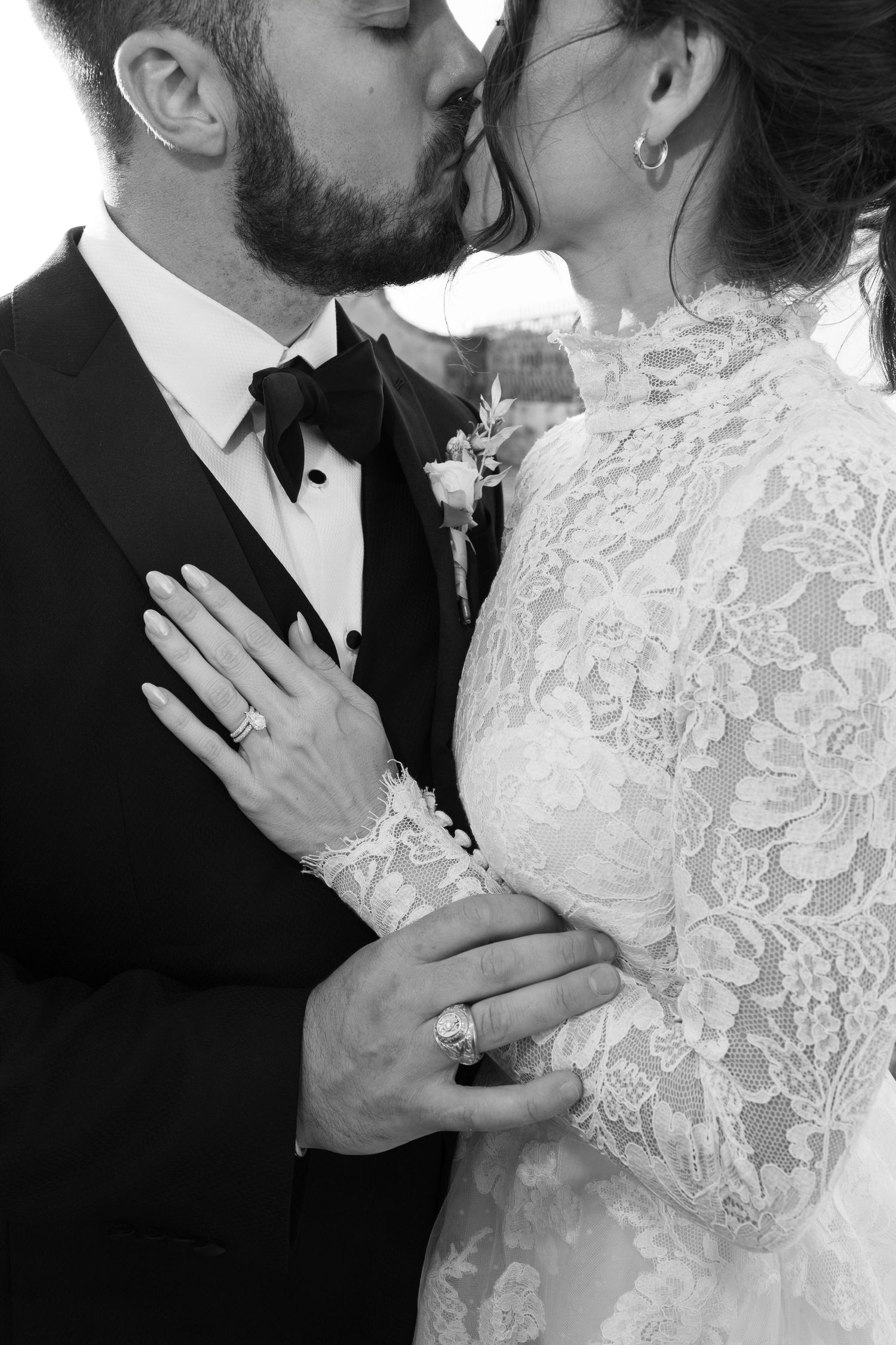 Close-up black and white sequence of a romantic wedding kiss between newlyweds in formal attire.