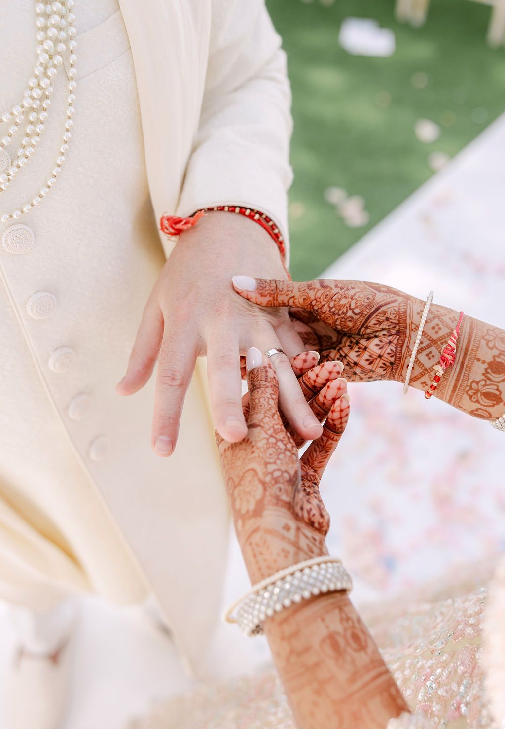 Close-up of hands with traditional henna designs and jewelry during an Indian wedding ceremony.