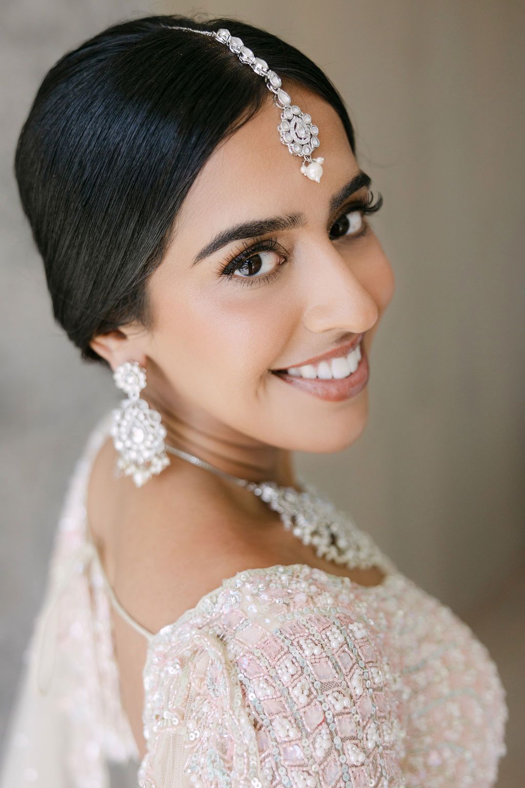Beautiful bridal portrait showcasing intricate crystal jewelry and embellished white gown details.
