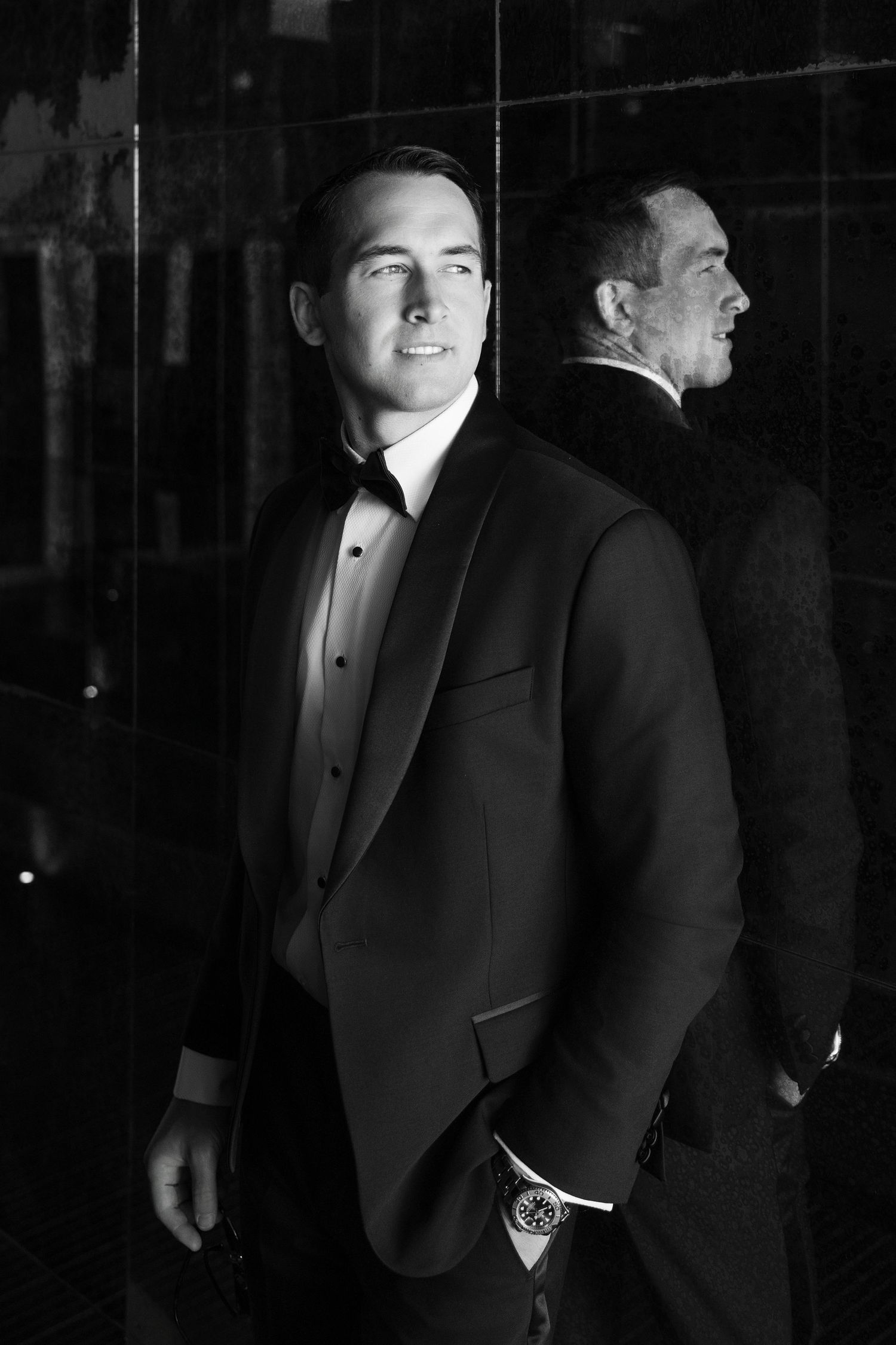 Men in formal black tuxedos photographed in dramatic lighting.