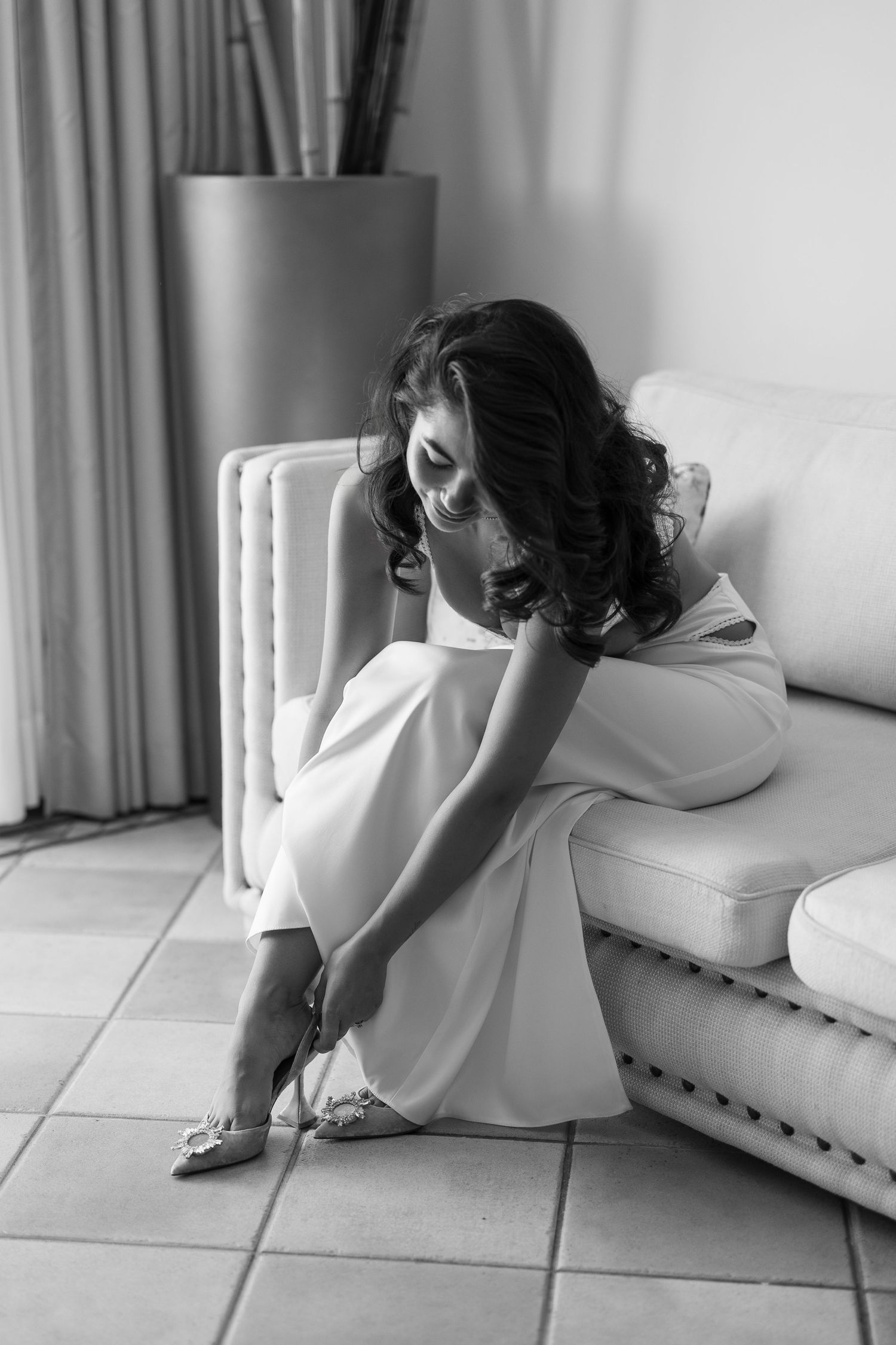 Black and white image showing someone adjusting details on the floor in a formal setting.
