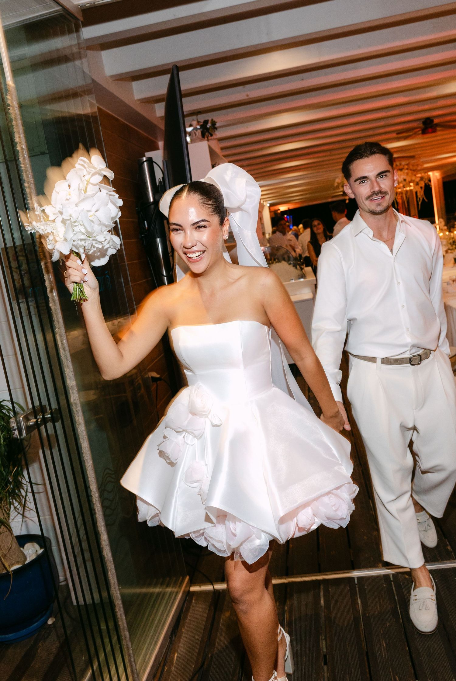 Wedding couple dancing and celebrating in formal white attire.