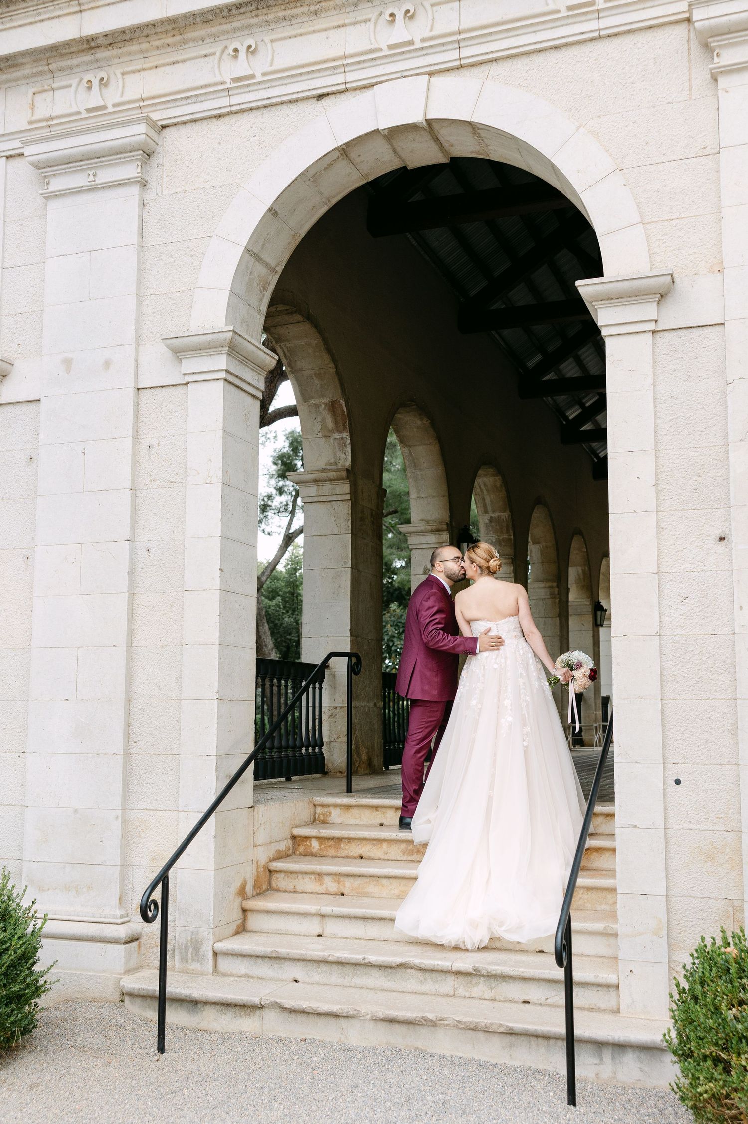 Elegant wedding photos taken under white stone archways of a historic building.