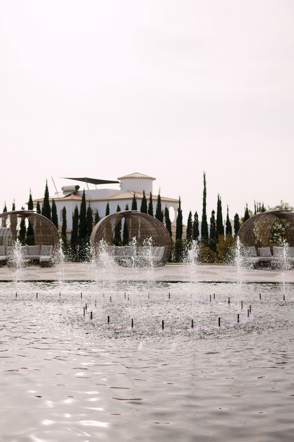 Mediterranean style villa with cypress trees and water fountains creating a serene landscape.