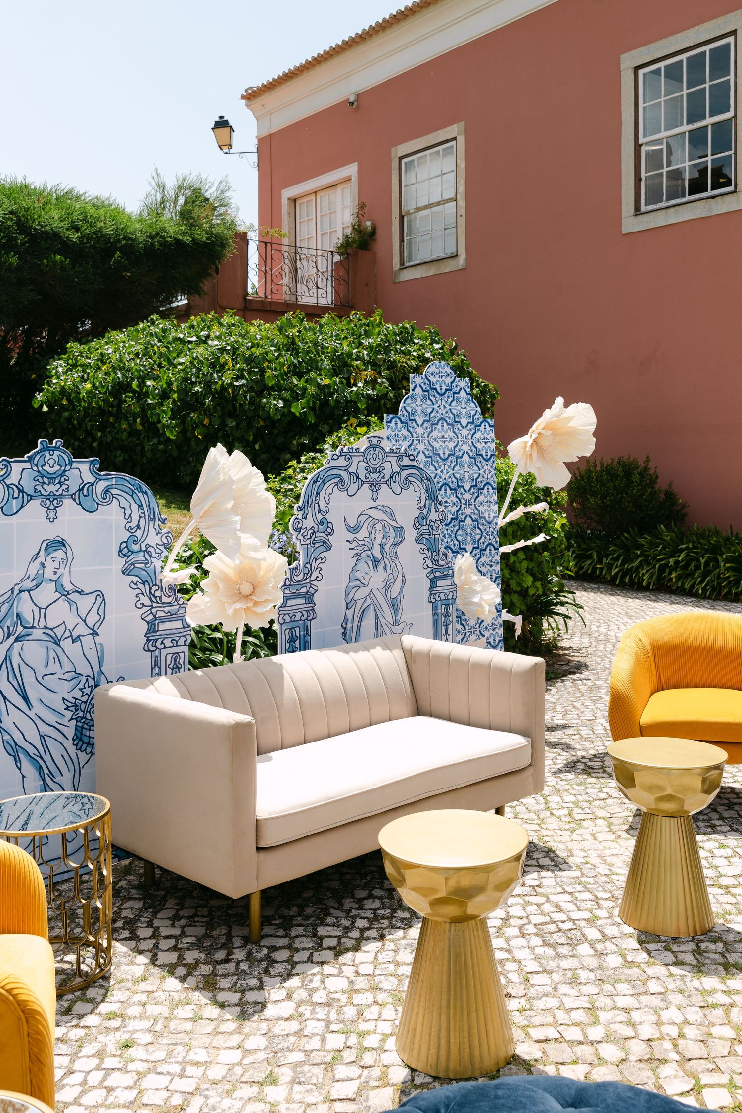 Modern lounge area with cream sofa and blue decorative panels against a coral-colored building.