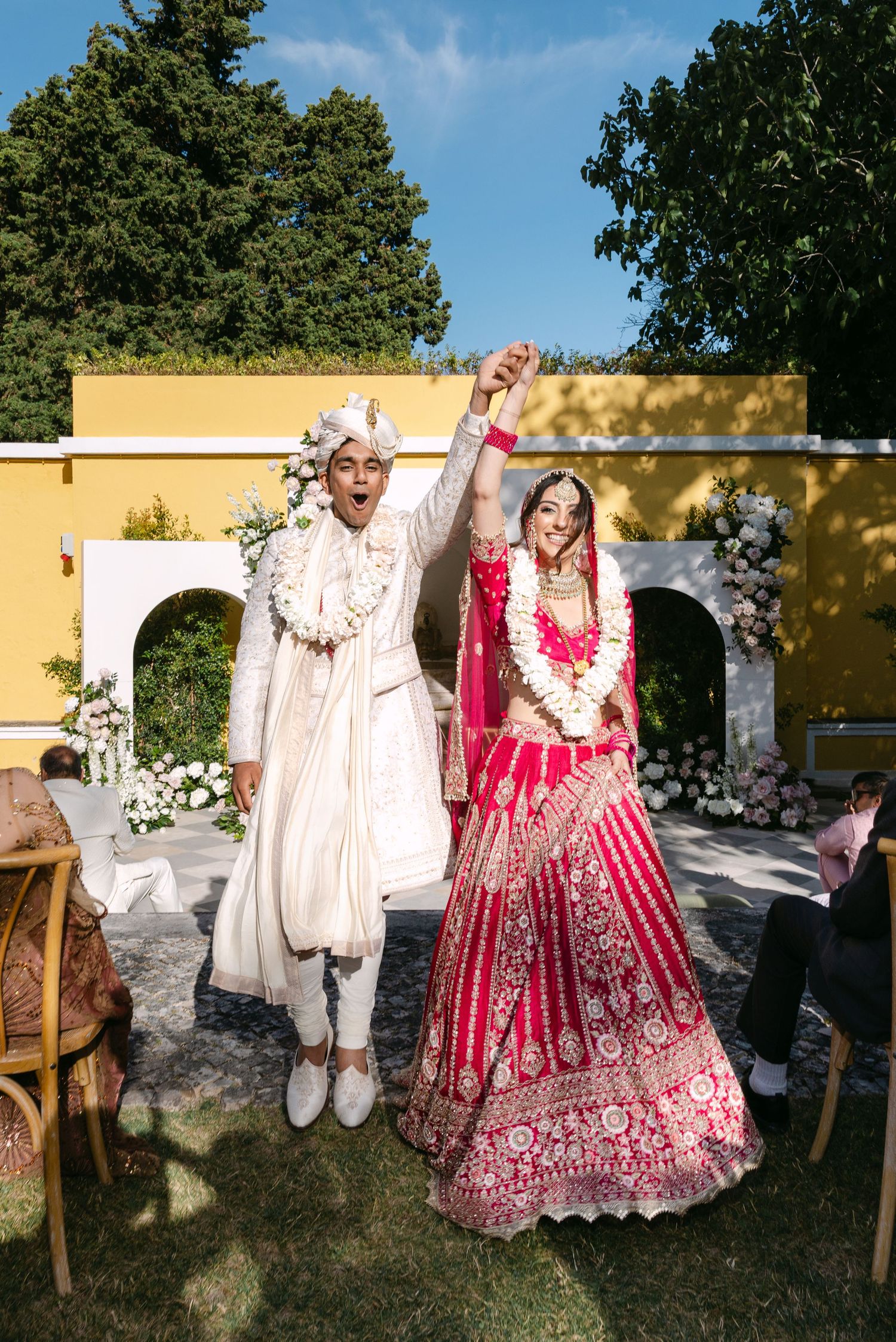 A couple celebrates during their fusion wedding ceremony wearing traditional Indian and western attire.