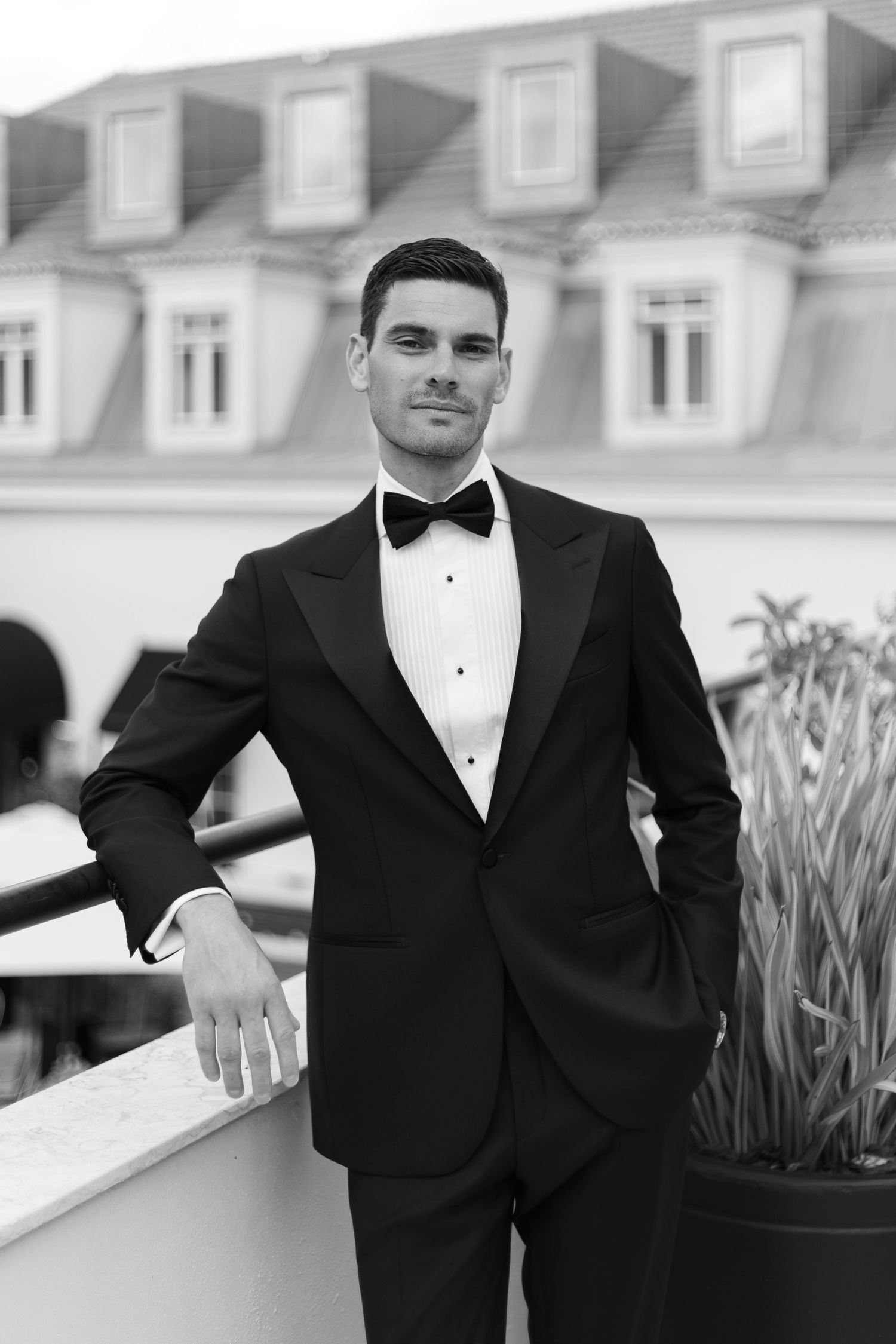 Formal event photography showing people in black tuxedos against architectural backdrop.