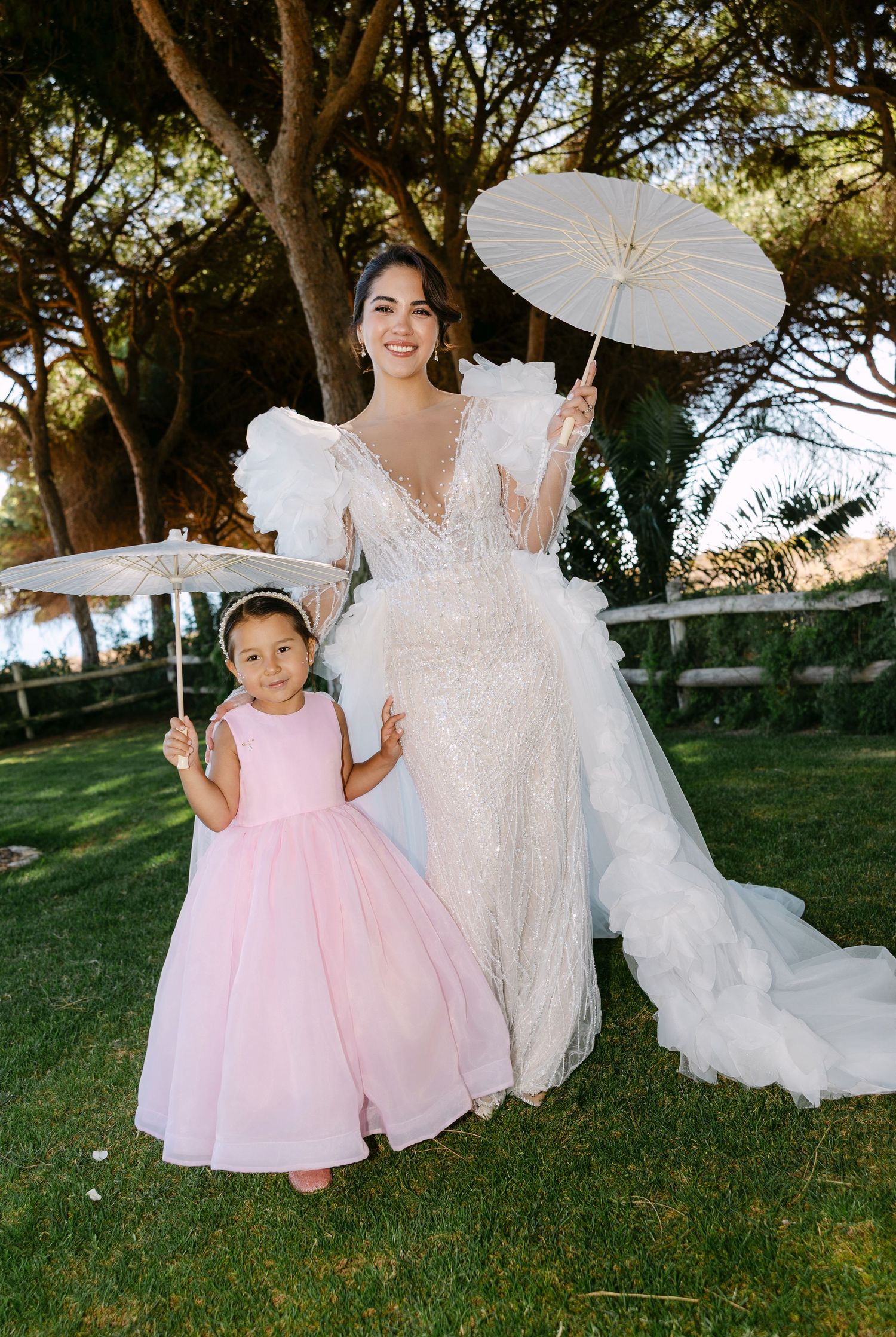 An elegant outdoor wedding scene with white parasols and formal attire.