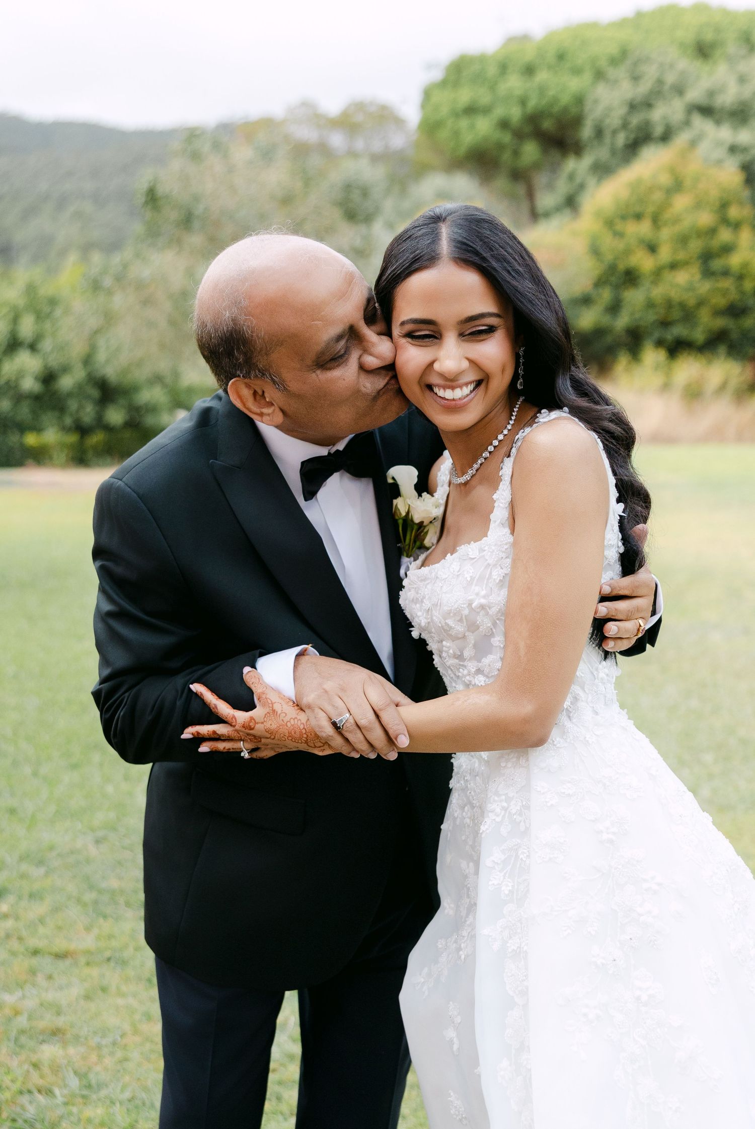 A tender moment shared between a couple in formal attire on their wedding day in an outdoor garden setting.