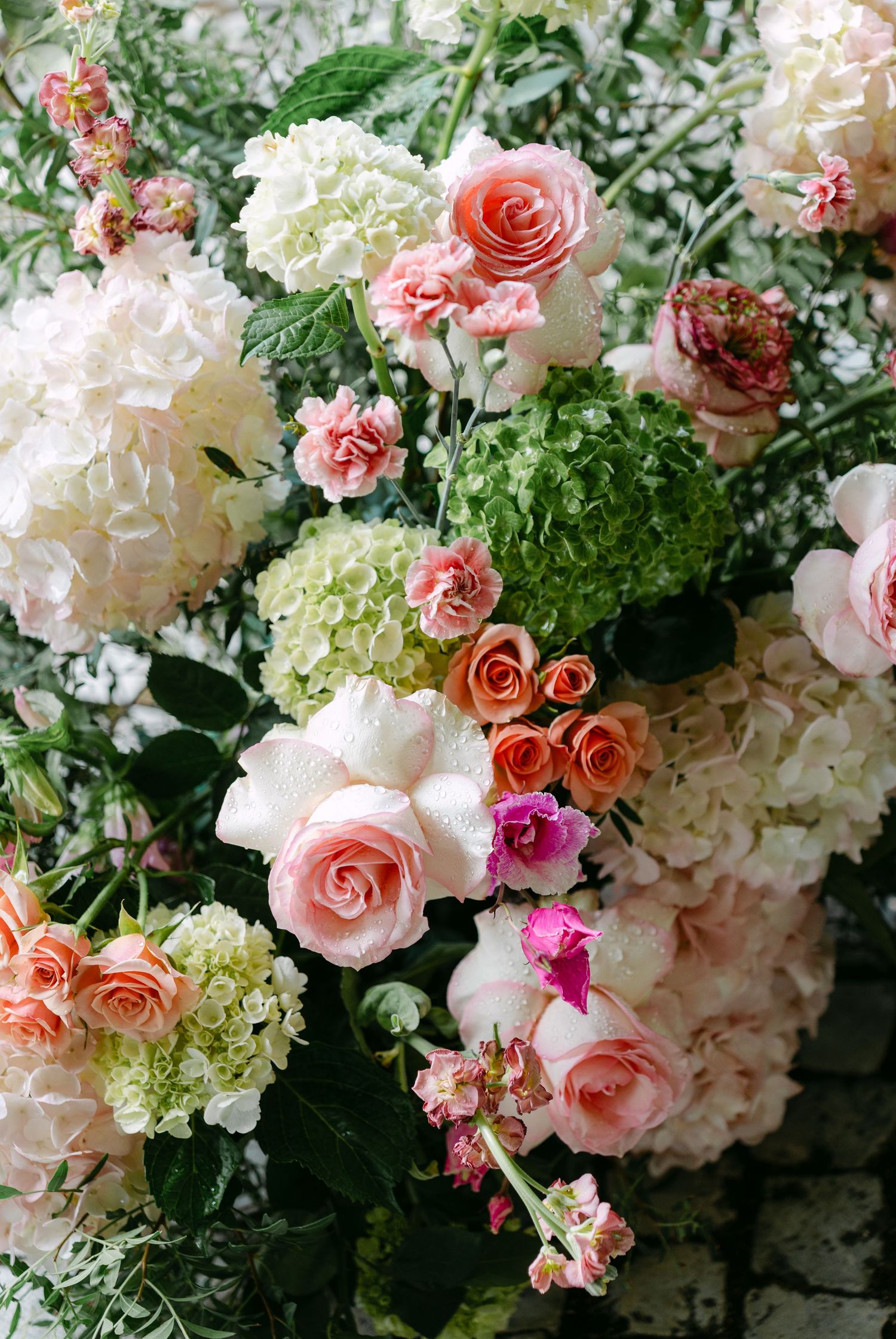 Elegant floral arrangement featuring pink roses, white hydrangeas and greenery in a romantic garden setting.