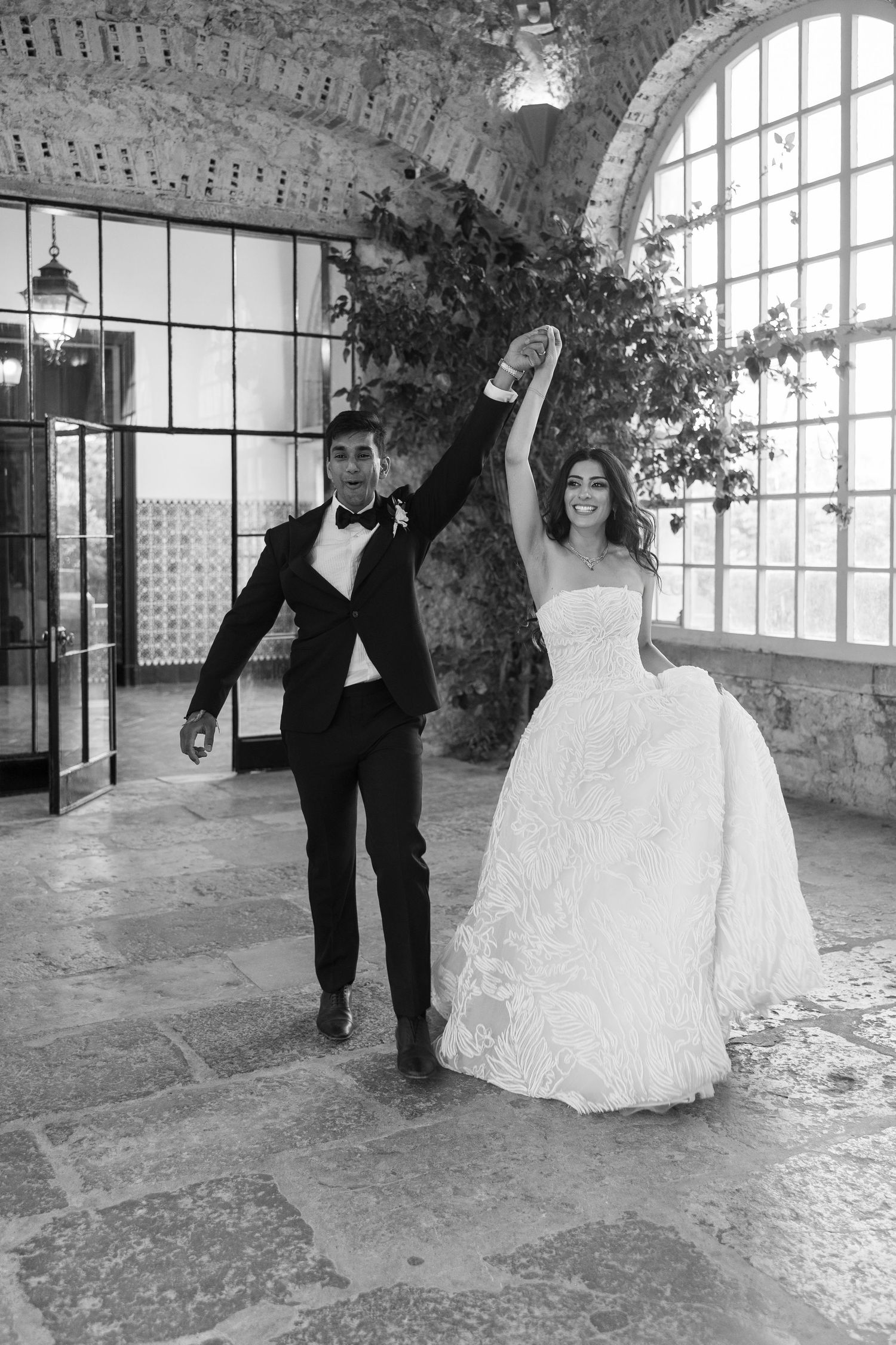 Joyful celebration moment in an elegant stone-walled venue with arched windows.