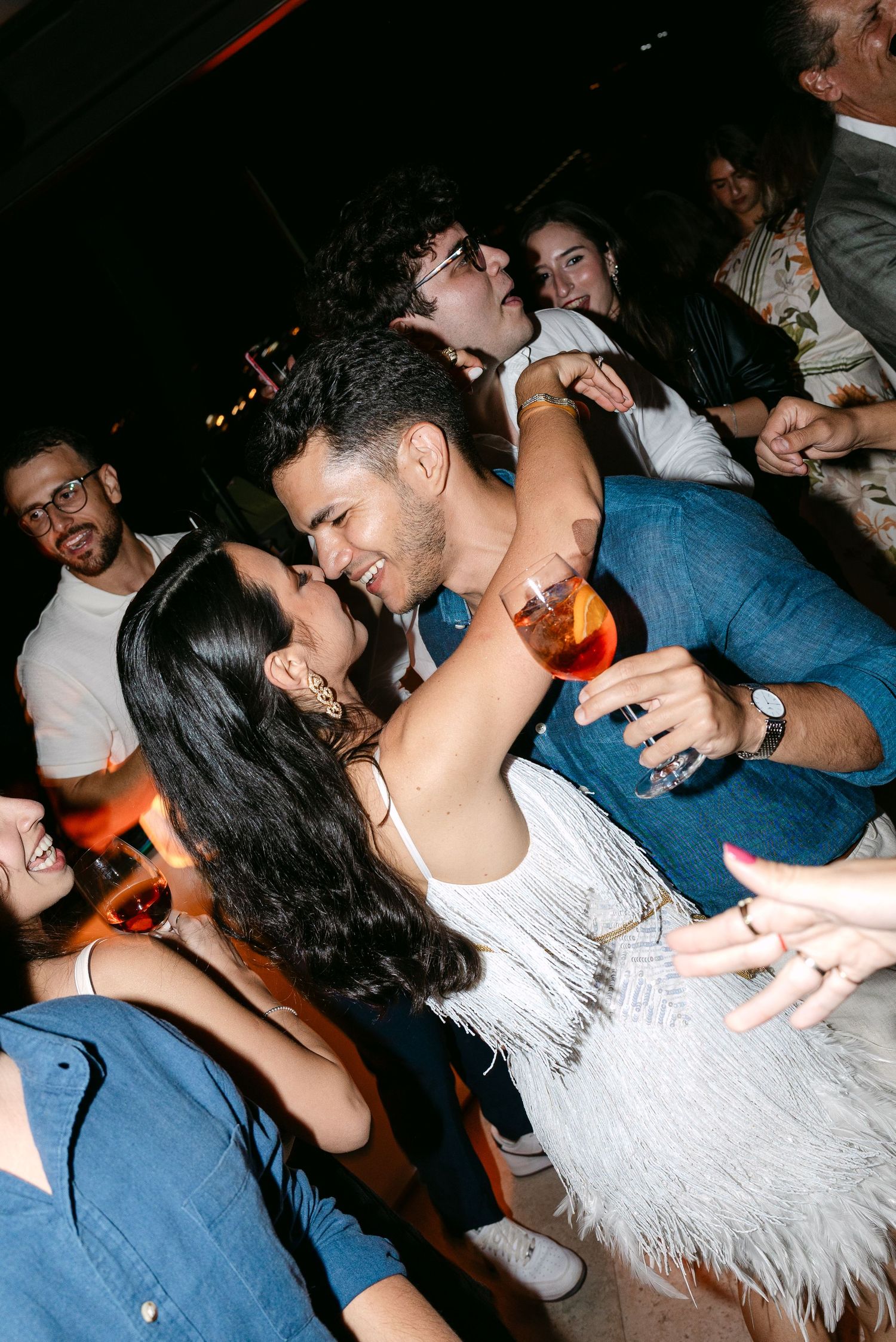 Candid moments of wedding guests dancing and embracing during reception party.