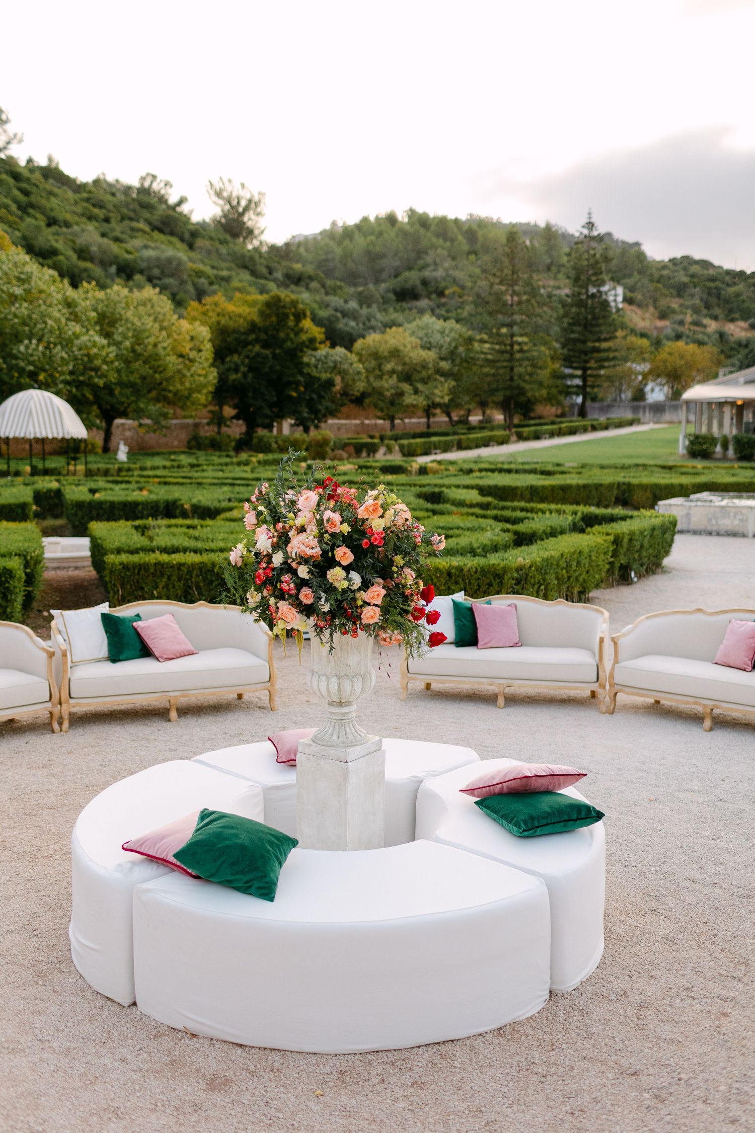 Modern outdoor lounge area with white circular seating and emerald green accent pillows.