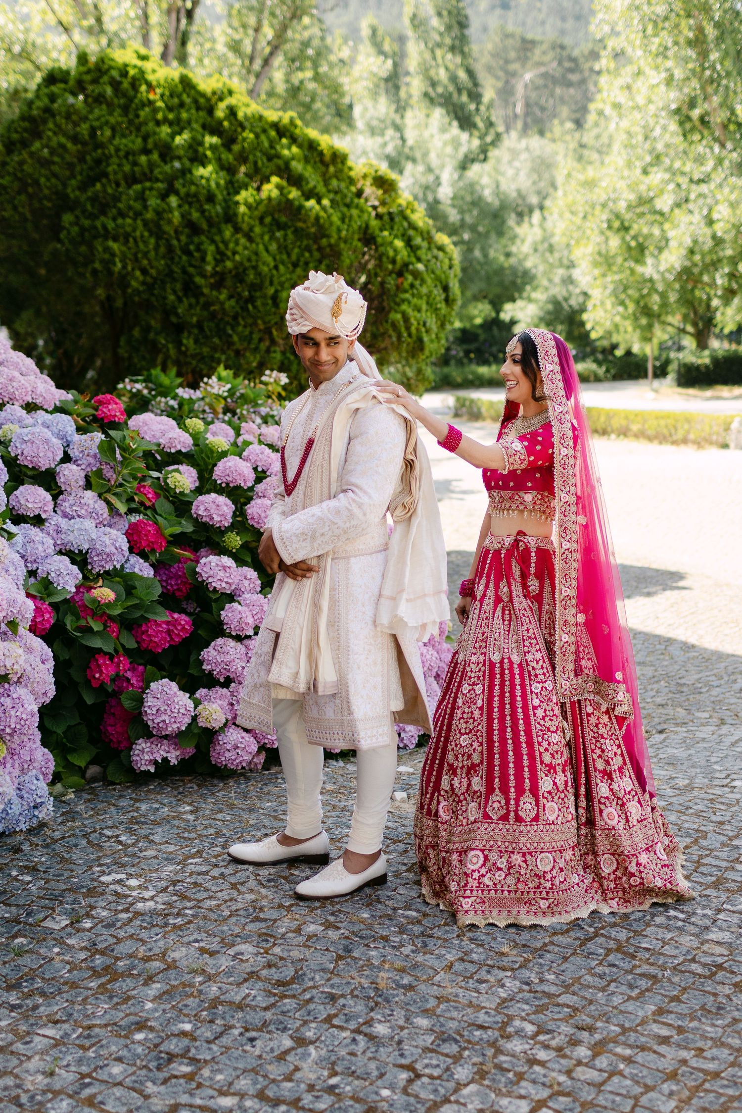 Outdoor wedding portraits with hydrangea bushes and cobblestone pathways featuring traditional Indian attire.